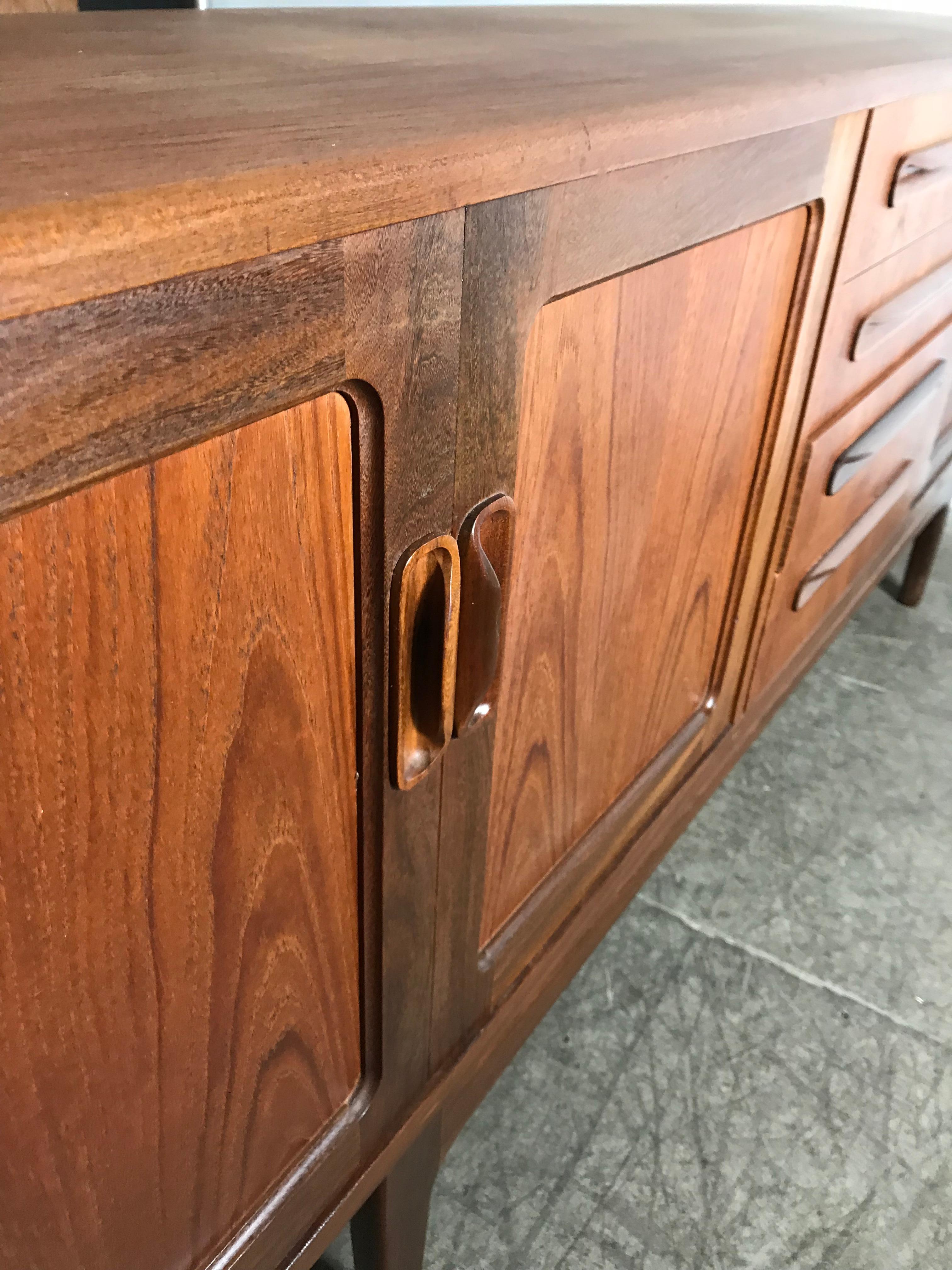 Stunning Danish modern credenza or sideboard by Kofod-Victor Wilkins teak wood construction, dovetail drawers. Featuring 4 drawers centre with top silverware drawer, 4 doors with shelf and amazing sculptural hand pulls. Beautiful bookmatched figured