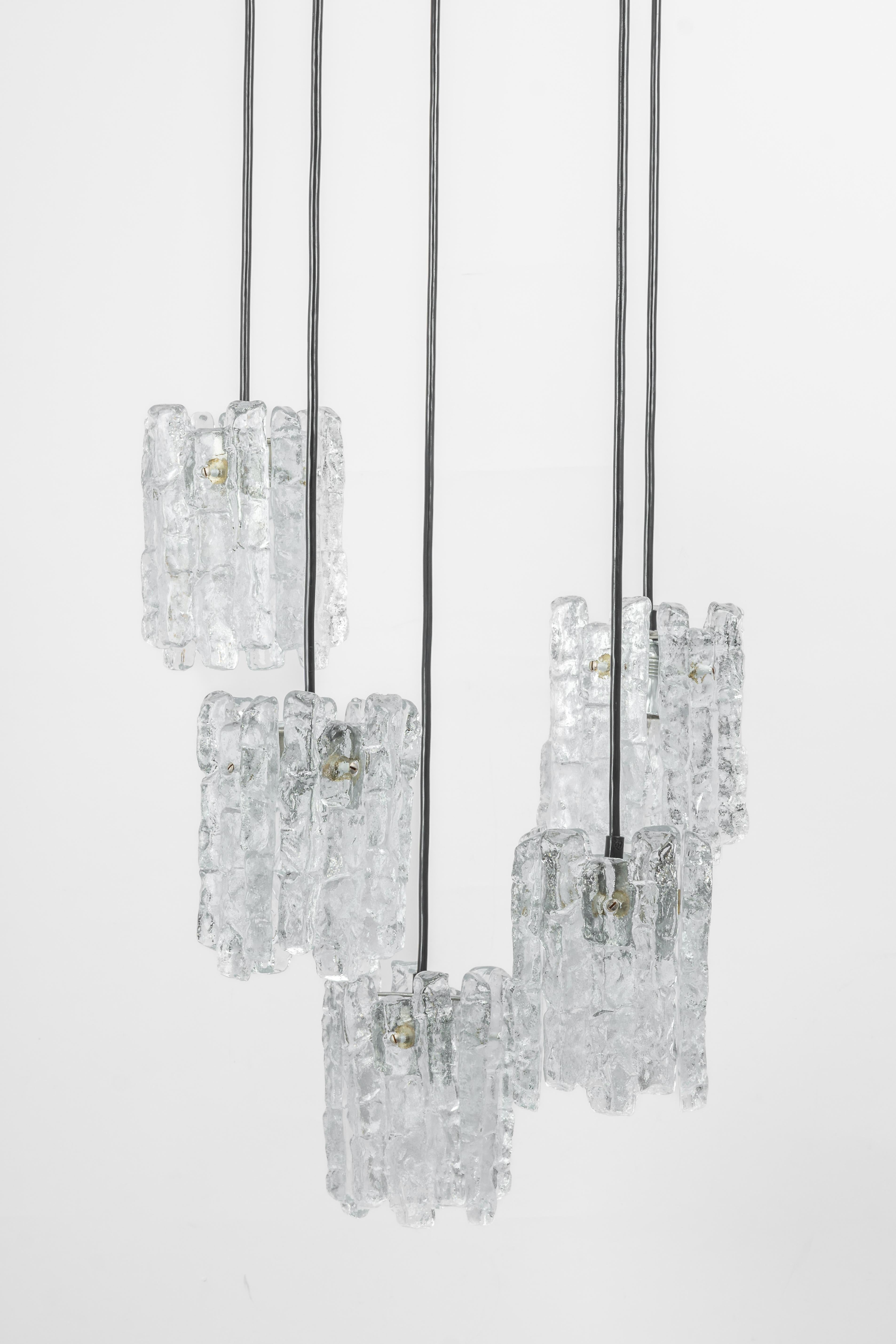 Ein spezieller, kaskadenförmiger Kronleuchter, entworfen von Kalmar, hergestellt in Österreich, ca. 1970er Jahre, mit fünf Gruppen strukturierter Murano-Gläser.
Atemberaubender Lichteffekt.
Fassungen: 4 x E14 Glühbirne klein. (je 40 W