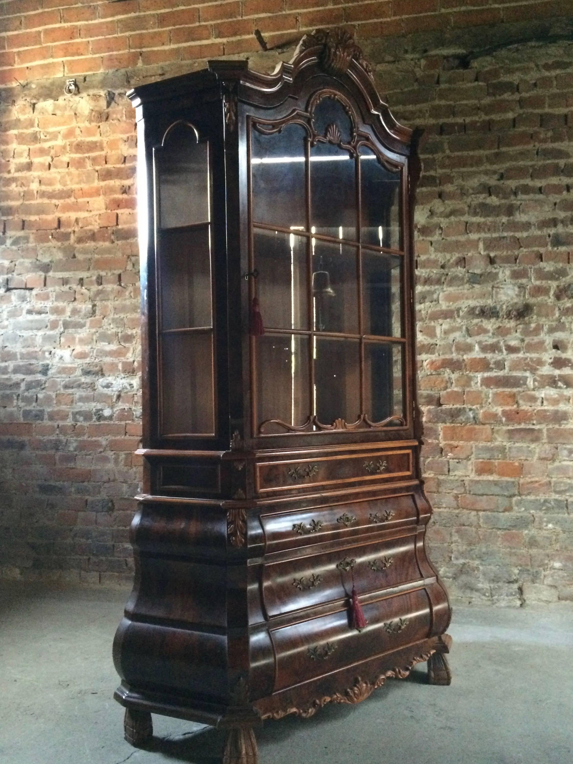 A fabulous 20th century Dutch walnut veneered display cabinet, the moulded shaped cornice over a pair of glazed doors with canted sides, the interior fitted with display shelves, over slim frieze drawer raised on a bombe base with three graduated