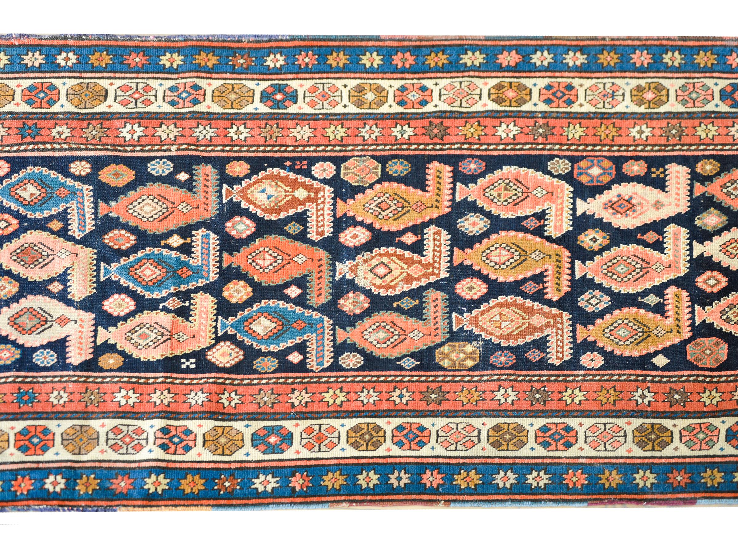 A stunning early 20th century hand-knotted Persian Karabagh rug with an all-over pattern of multi-colored paisleys amidst a field of petite stylized flowers set against a dark indigo background. The border is wonderful with a central stylized floral