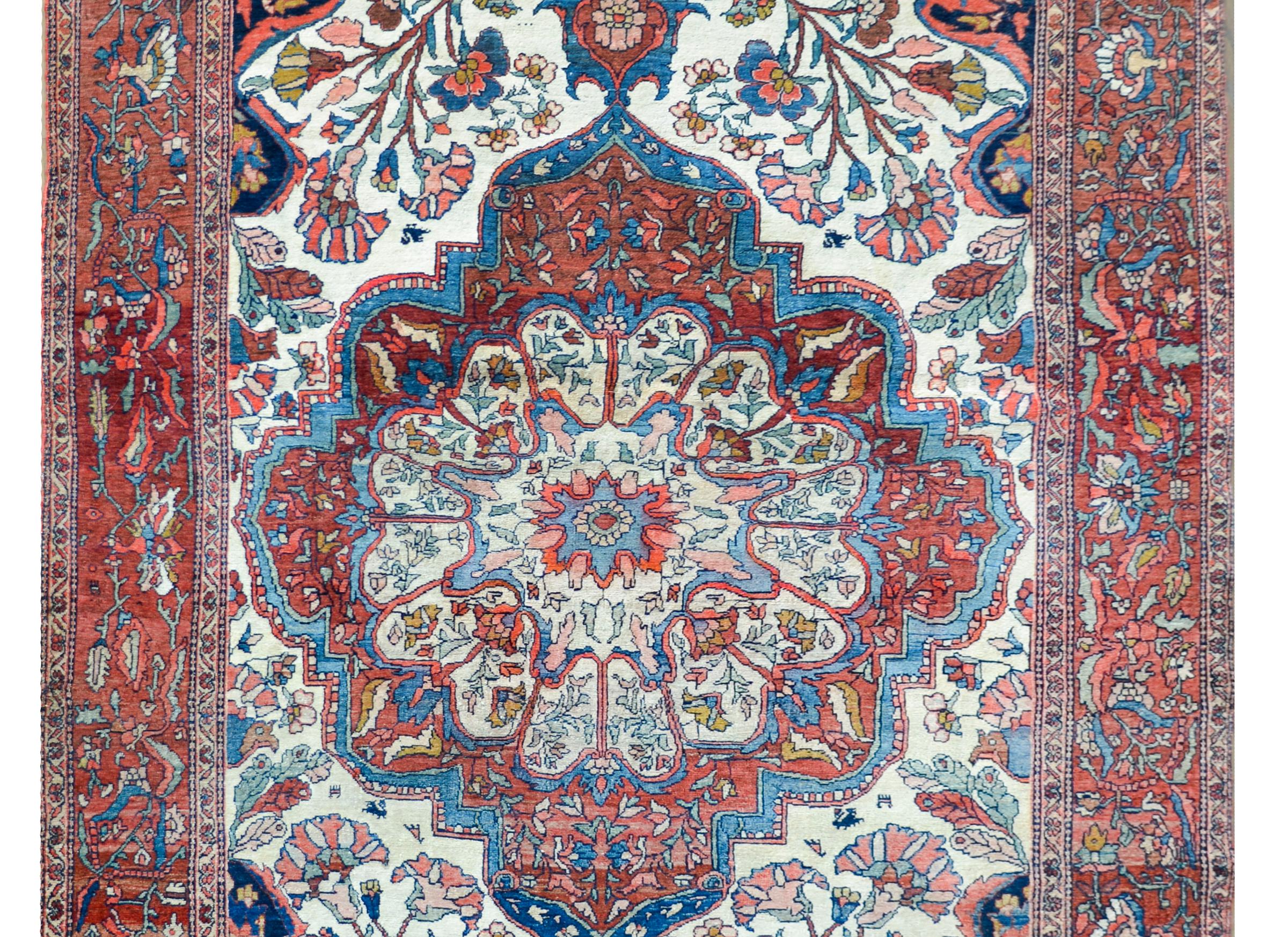 A stunning early 20th century Persian Sarouk Farahan rug with a large central floral medallion woven in incredible reds, pinks, oranges, and indigos, and set against a white field with mirrored floral clusters all woven in similar colors as the