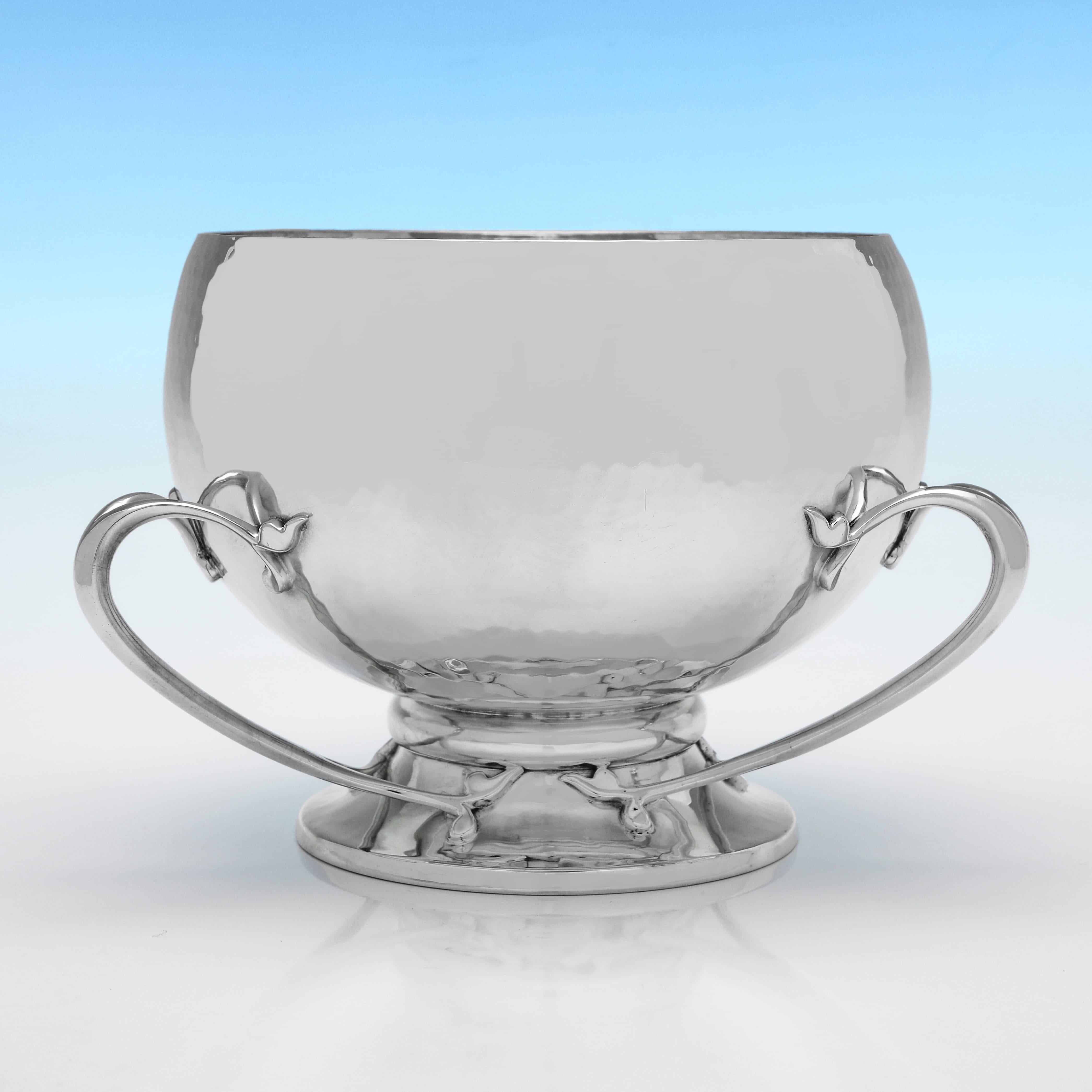 Marchiata a Londra nel 1904 da Wakely & Wheeler, questa elegante tazza in argento sterling antico edoardiano, dal design Arts and Crafts, presenta una finitura martellata a mano e tre manici naturalistici. La tazza, o tyg, misura 5,5