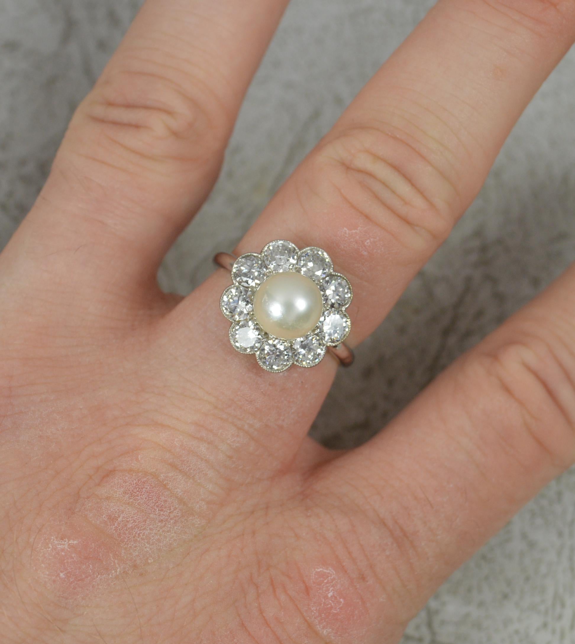 A stunning, true Edwardian period ring.
Solid platinum shank and setting.
Designed with a pearl to the centre, 7mm diameter. Surrounding are nine natural, old cut diamonds, set into full grain bezel settings. Approx 2.00 carat total weight, clean