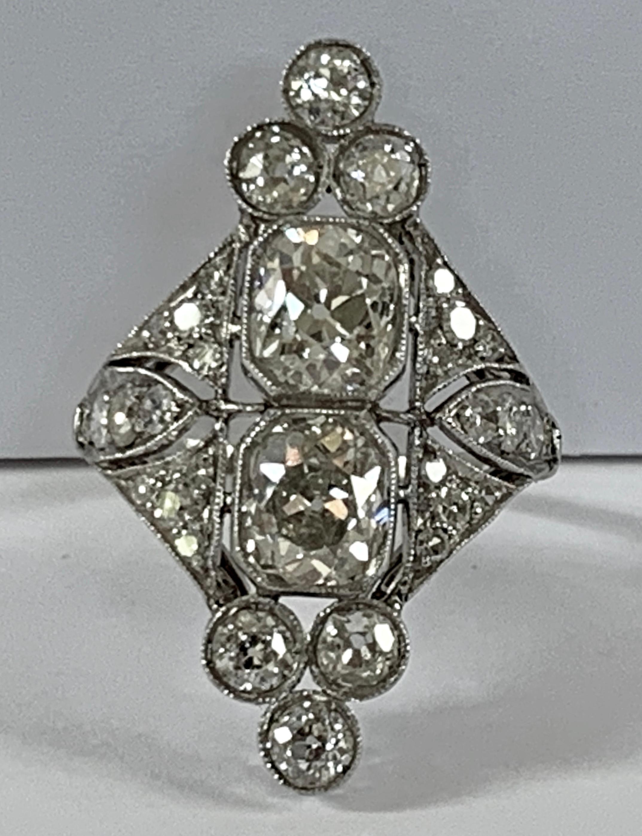 Stunning Art Deco ring showcases two nearly identical Old European cut tinted diamonds of circa 3.20 ct.  
The diamonds rest in a low profile platinum setting with delicate milgraining and open work filigree detailing. The 2 central stones are