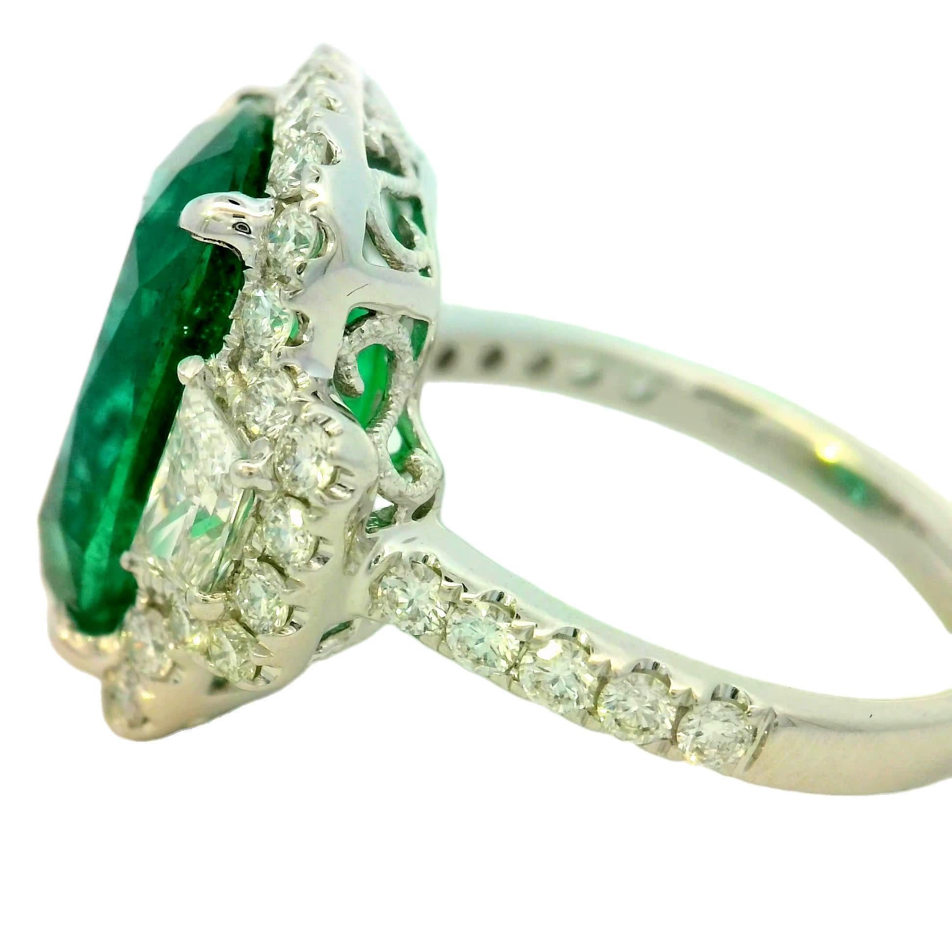 In der Mitte dieses exquisiten Rings befindet sich ein atemberaubender Smaragd, der von funkelnden Diamanten umgeben ist, die seinen leuchtend grünen Farbton unterstreichen. Mit Präzision gefertigt, ist es ein perfektes Statement für jede