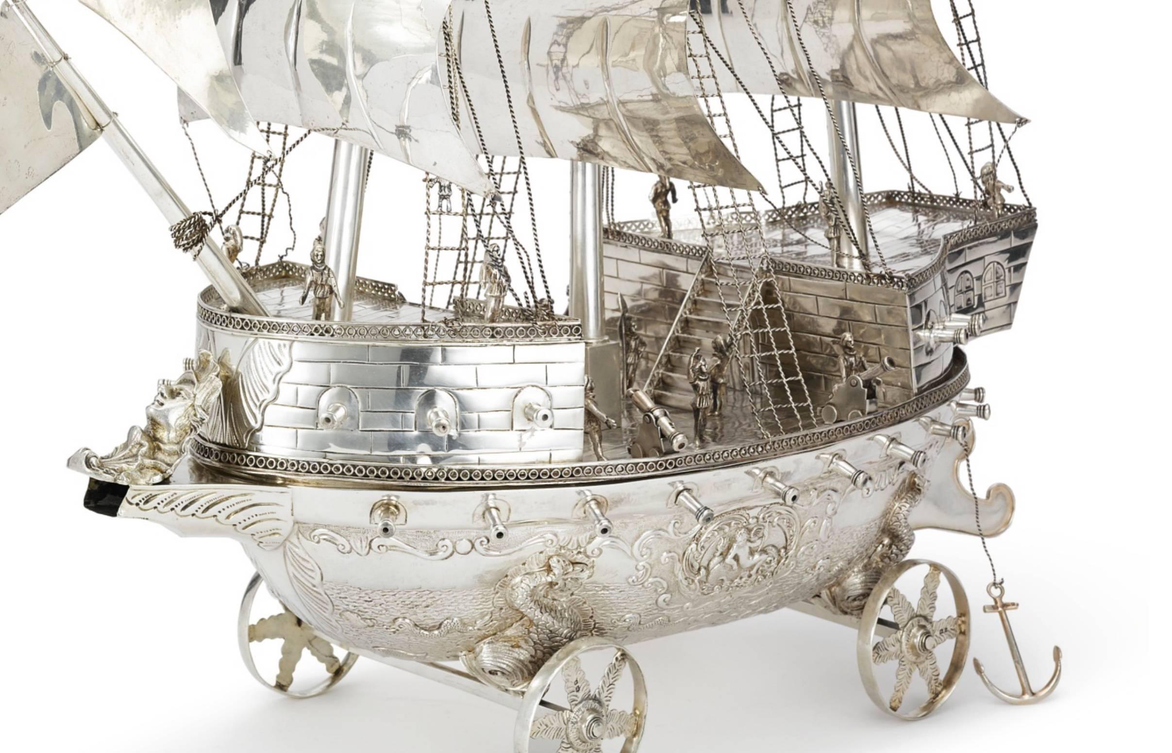 An absolutely stunning and rare sterling silver Neff. Superb quality and detail, and an unusual size.
This three masted neff is fully manned and rigged with sailors, the deck detachable, the hull with putti riding dolphins and numerous fish and