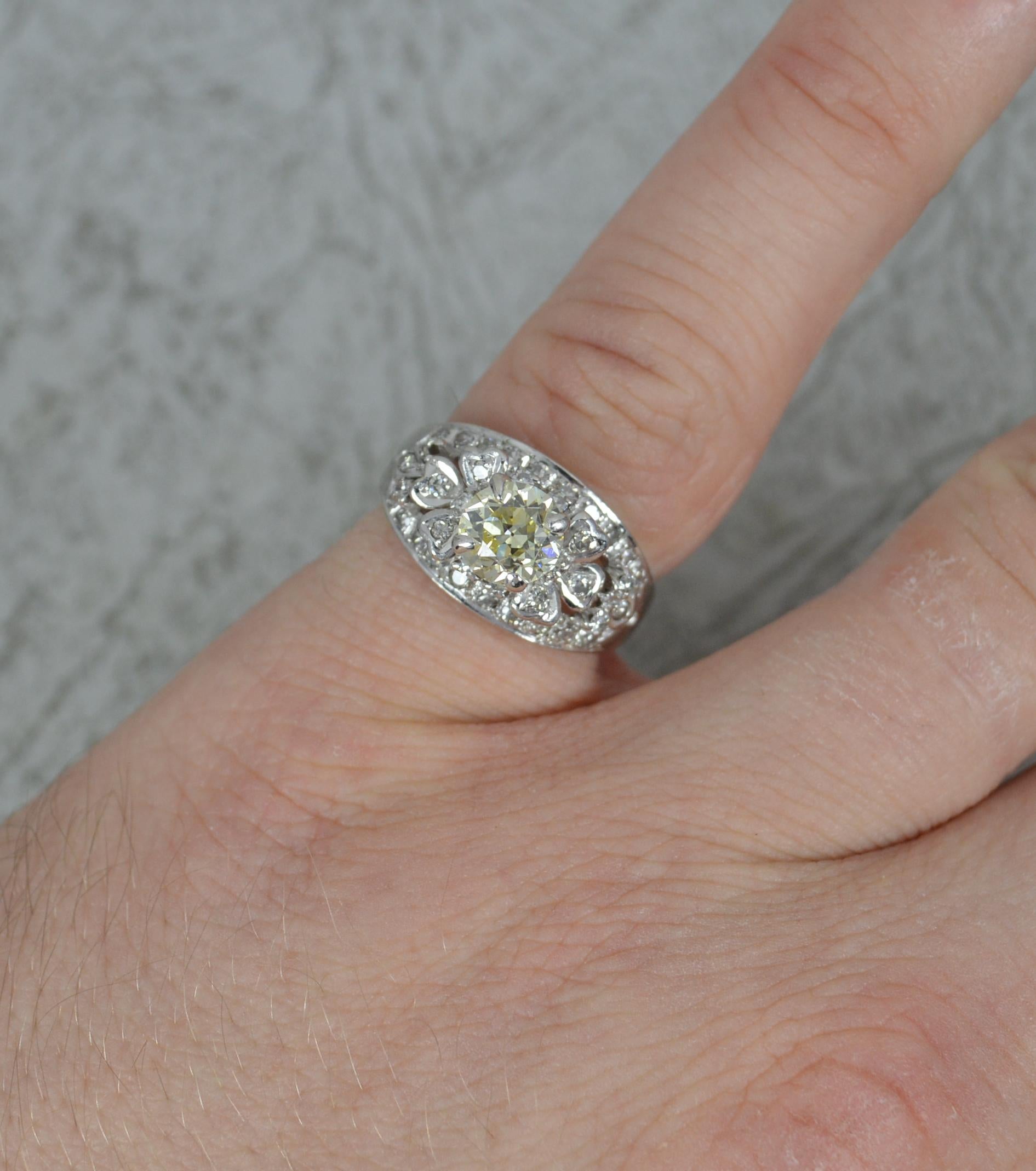 A superb quality antique cluster engagement ring.
Solid 18 carat white gold example.
Set with a natural, 6mm diameter, 0.85ct old cut diamond to the centre in a four claw setting. Natural, fancy yellow colour. Set above, below and to the sides are
