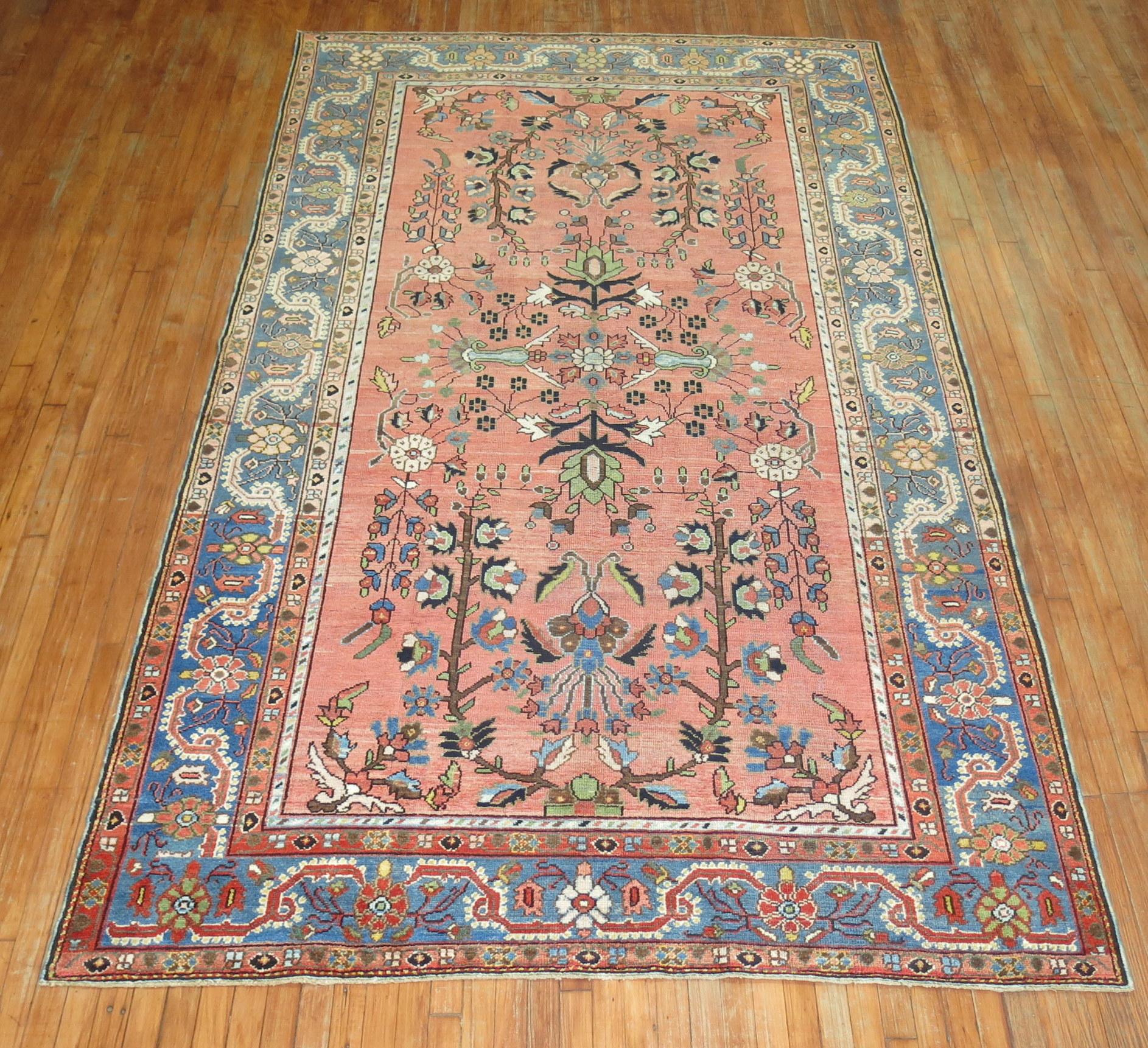 20th century Persian Malayer rug featuring a paradise floral motif on a pink ground surrounded by a soft blue border, circa 1920.

Measures: 6'6” x 11'.