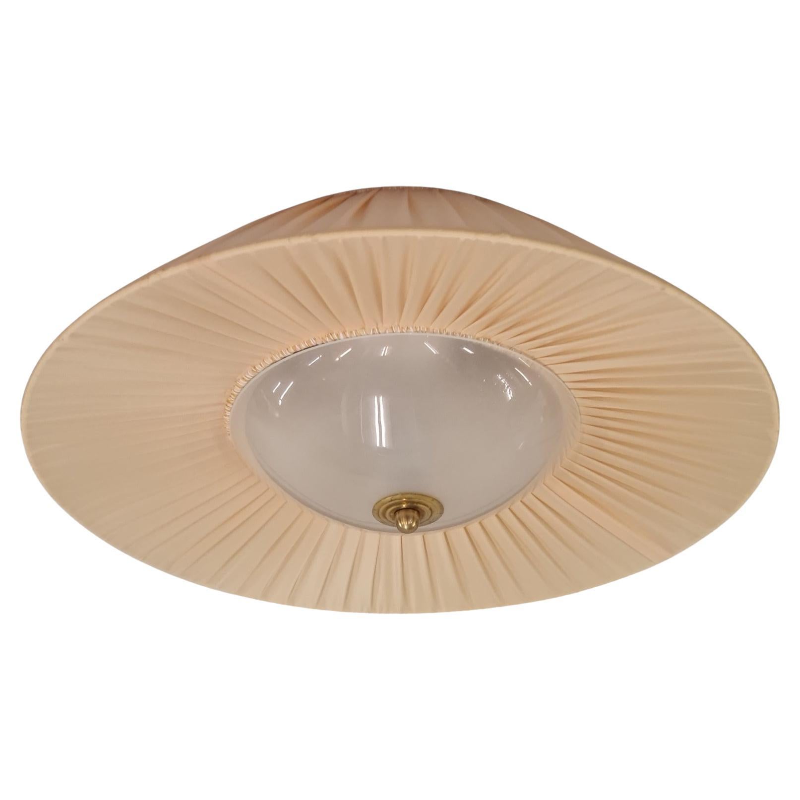 A stunning light fixture with glass shade surronded by a silk or silk like fabric held with a brass nob. The effect from the fabric shade combined with the glass diffuser is quite magnificent and truly gives a cozy ambience and will add warmth to