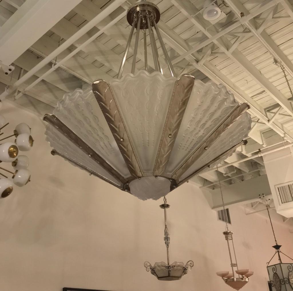 Stupendo lampadario francese Art Deco dell'artista francese Gênet et Michon. Ha nove pannelli con una coupe centrale in vetro trasparente e smerigliato. Montato in una cornice geometrica lucida in bronzo argentato. È stato ricablato per l'uso