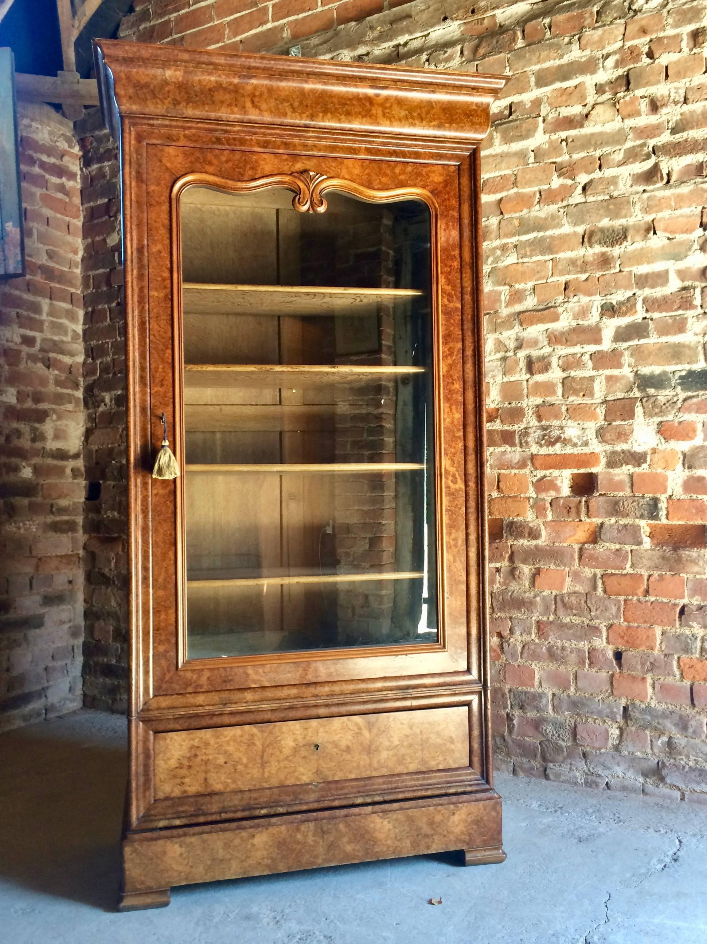 A beautiful large and imposing antique 19th century French burr walnut glazed bookcase cabinet vitrine, circa 1865, the corniced over a single glaze door with scalloped shaped glass, four full length adjustable shelves within, single pull out drawer