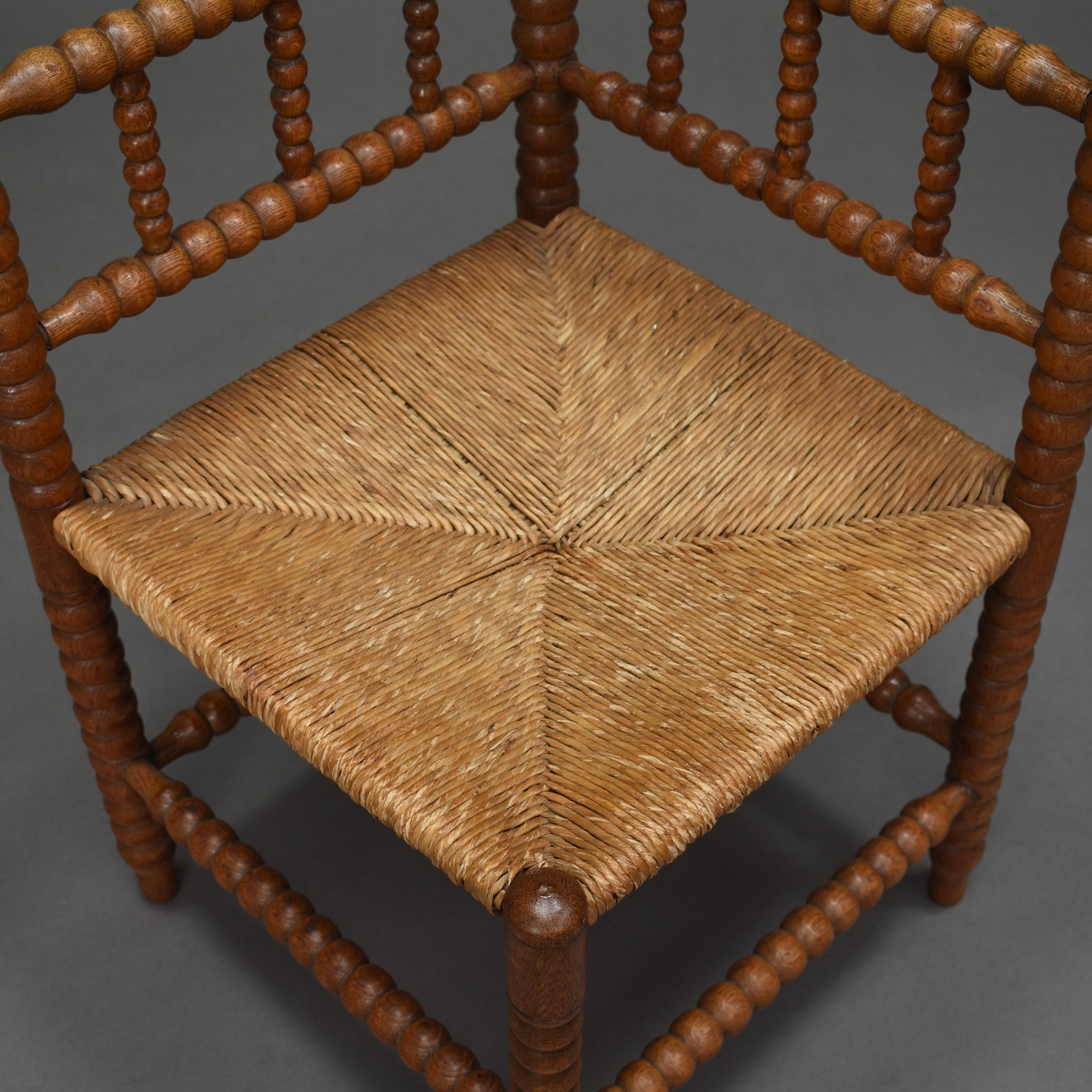 Wunderschöner französischer Eckstuhl aus massivem, gedrechseltem Eichenholz mit originalem Sitz aus geflochtenem Schilfrohr, um 1930-1940. In sehr gutem Zustand. Ein Bein ist natürlich leicht angewinkelt. Der Stuhl ist strukturell solide und der