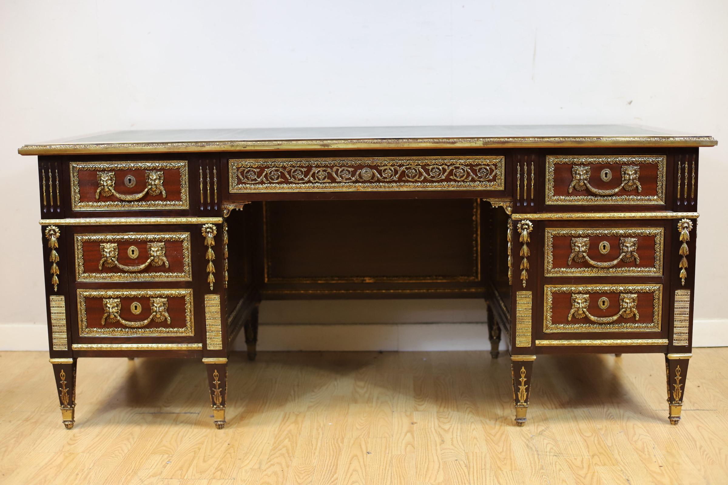 We delight to offer sell this stunning large French Empire style walnut desk having a gilt tooled green leather top with a ormolu edge and scrolling mounts flanked by an arrangement of six short drawers with faun's head handles sitting between two