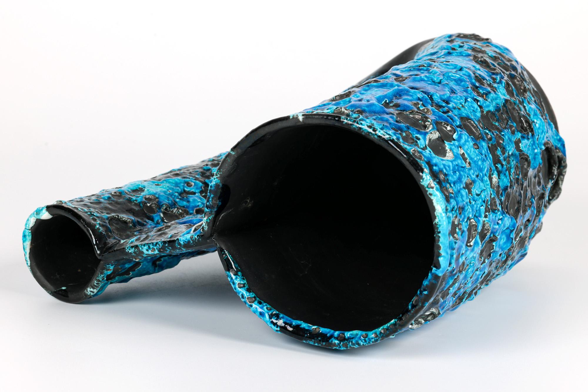 A stunning and unusual French mid-century turquoise and black lava glazed twin stem vase formed in the style of a jug dating from around 1950/60. The red earthenware vase stands on a narrow round base with a U-shaped body with a squeezed flattened