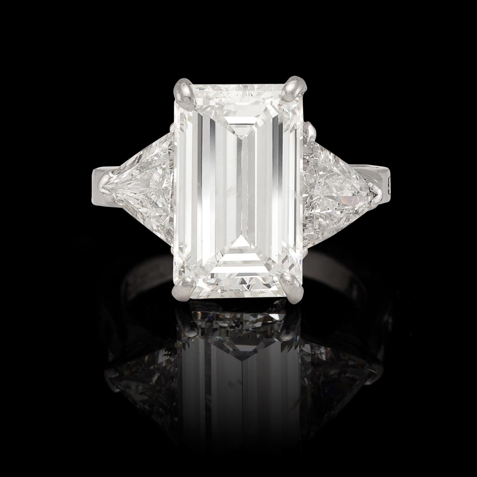 A superb platinum ring, featuring an incredibly bright 6.23- cts. emerald-cut diamond, with GIA grade of G/SI2, and set on either side with triangular-cut diamonds, weighing together an estimated 3.10 carats. The ring weighs 11 grams, and is