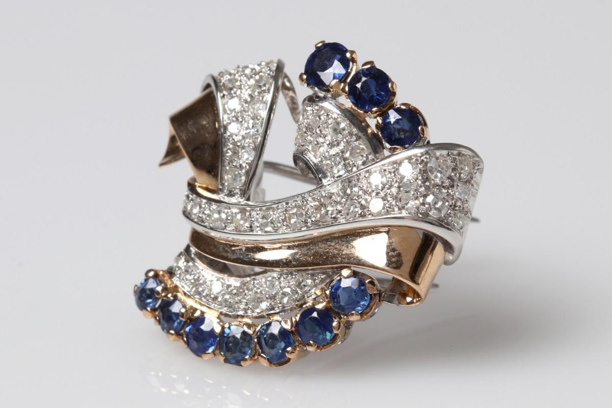Brooch made of 18-karat yellow gold with elements of white gold, characterized by a sophisticated form.
Decorated with round, faceted blue sapphires weighing 0.65 ct and sparkly brilliant diamonds with a total weight of 1.00 ct.

Origin: Western