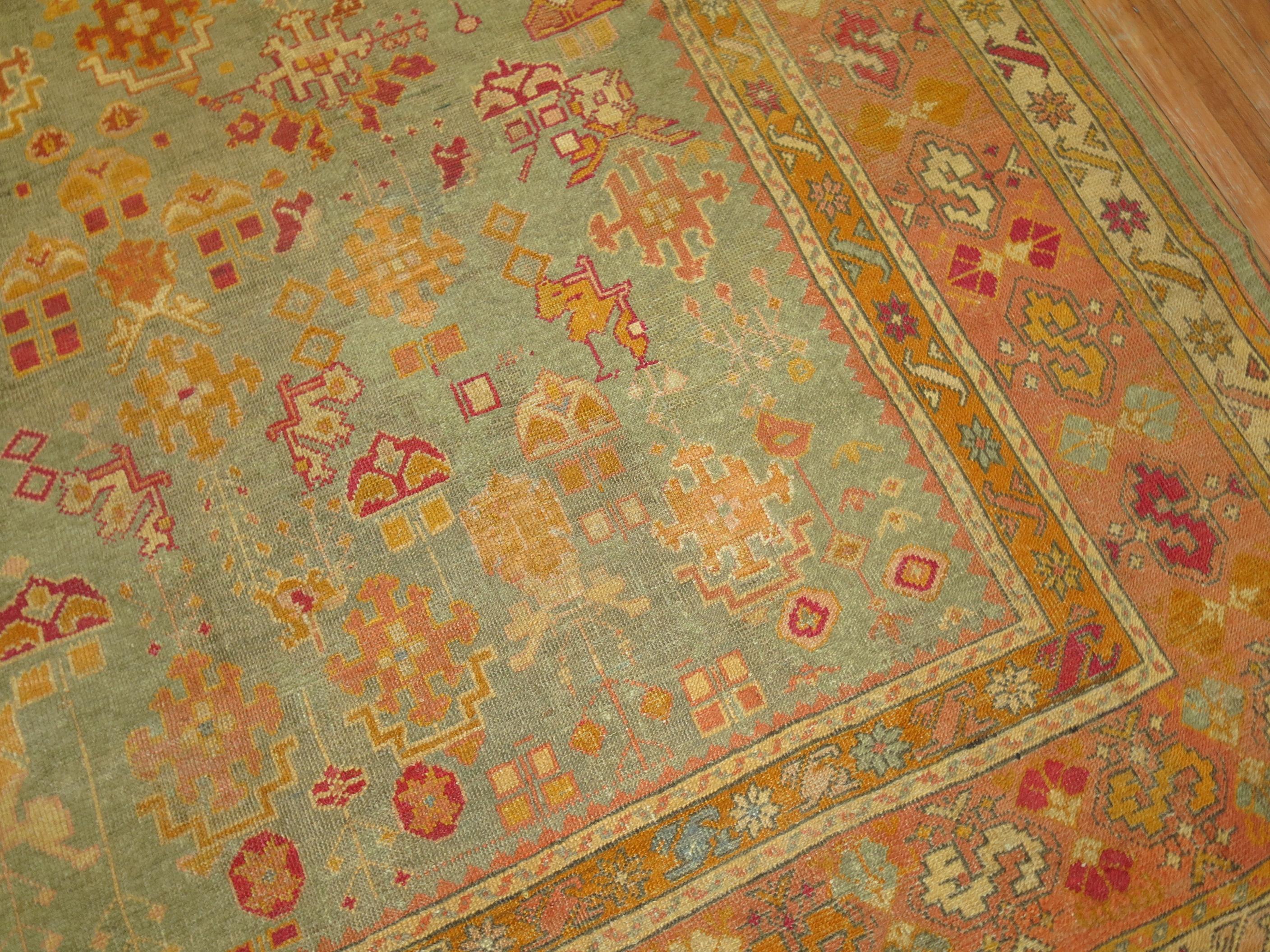 Stunning early 20th-century green field antique Turkish Ghiordes rug. Accents in orange, red, goldenrod, pink, and raspberry simmer throughout 

Measures: 8'8