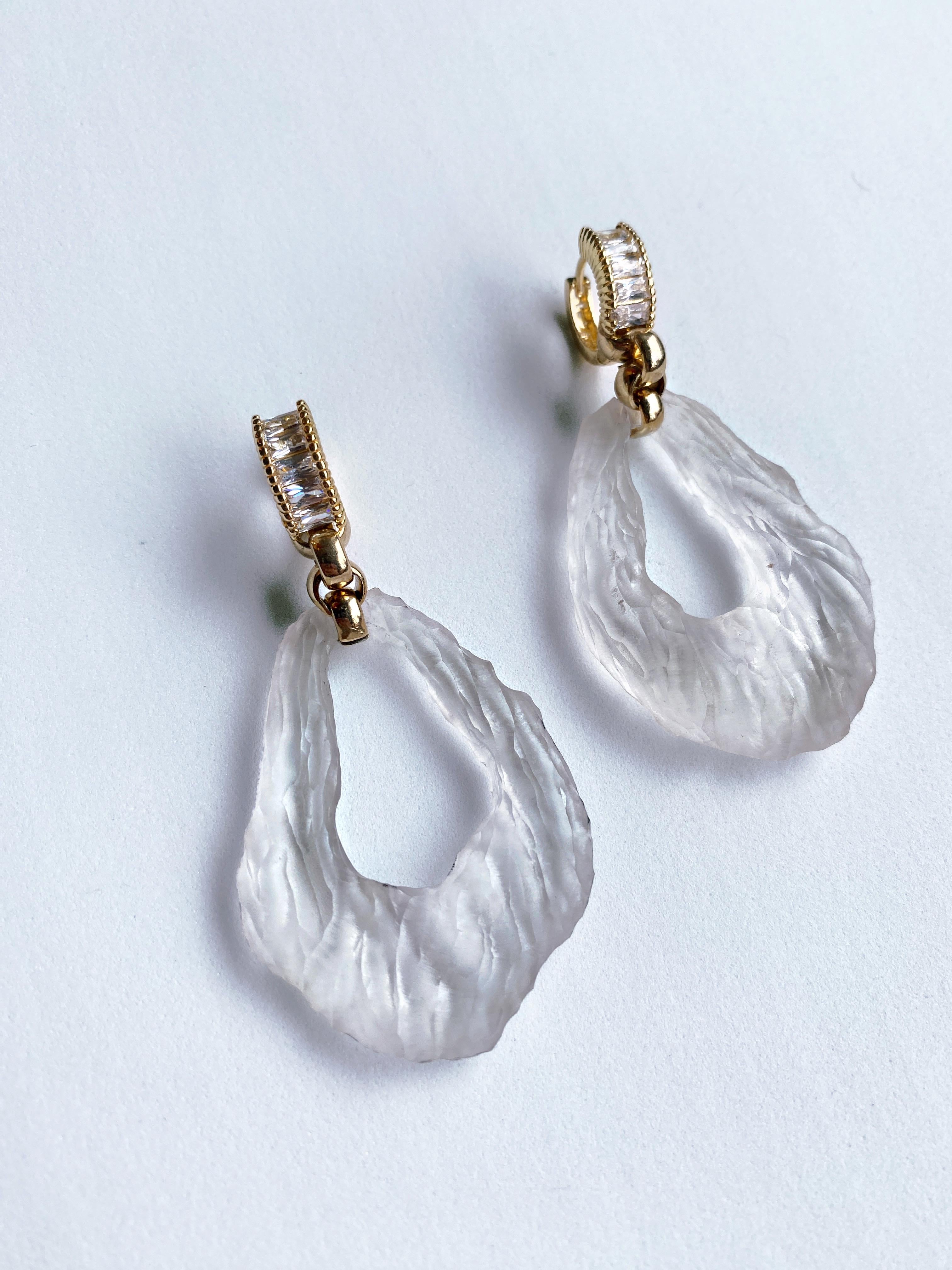 These stunning hand carved earrings by Sebastian Jaramillo, are made using discarded single used plastic. Delicately carved  and polished to resemble rock crystal and accented with gold finish and Swarovski crystals, make these earring lightweight,