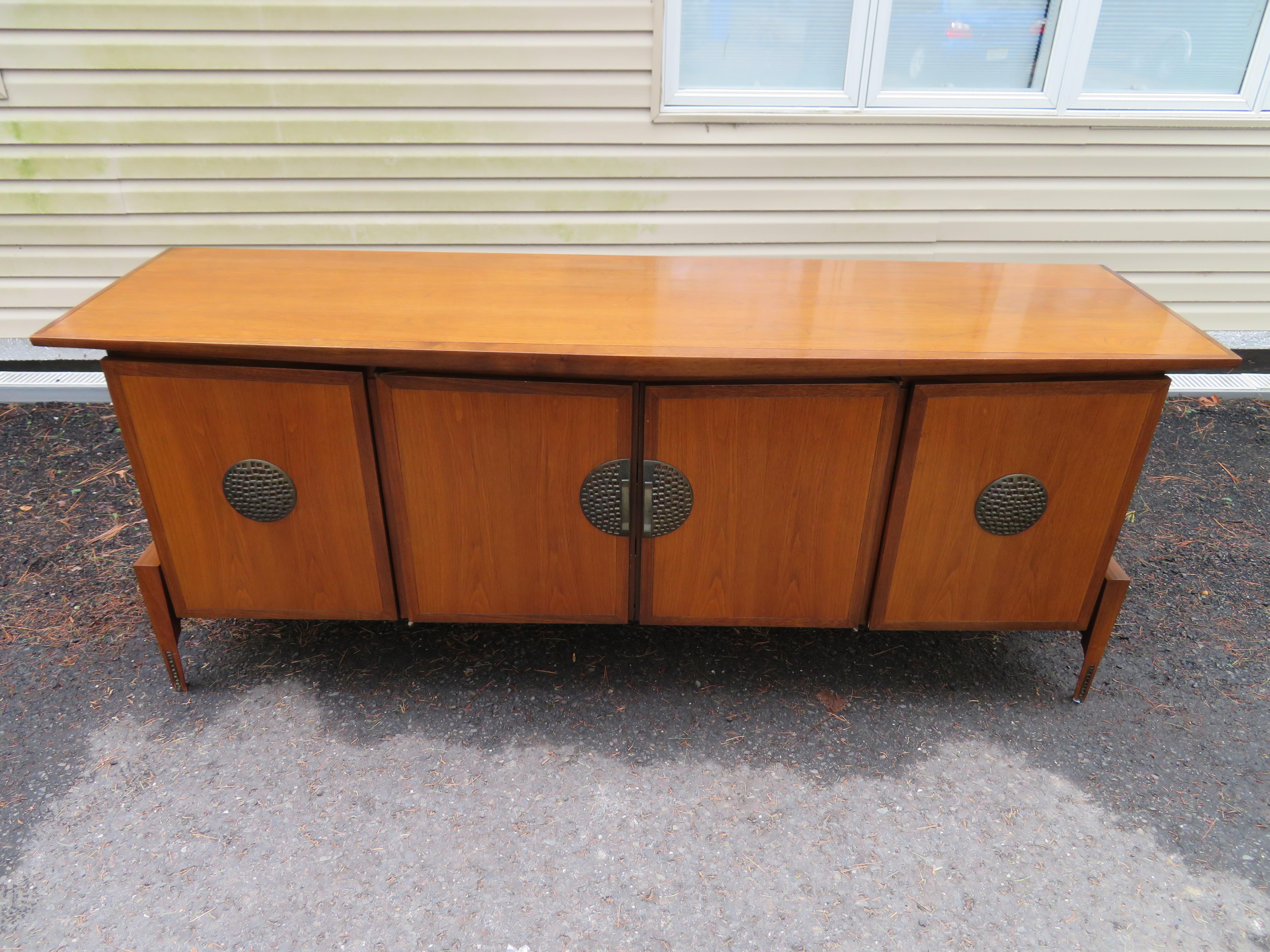 On par with Dunbar, Widdicomb and Wormley, this rare walnut, Hobey Helen Baker credenza boasts a “boomerang” style curved front, four beautiful walnut doors that open to three interior drawers on both sides and sits cradled on tapered legs. The