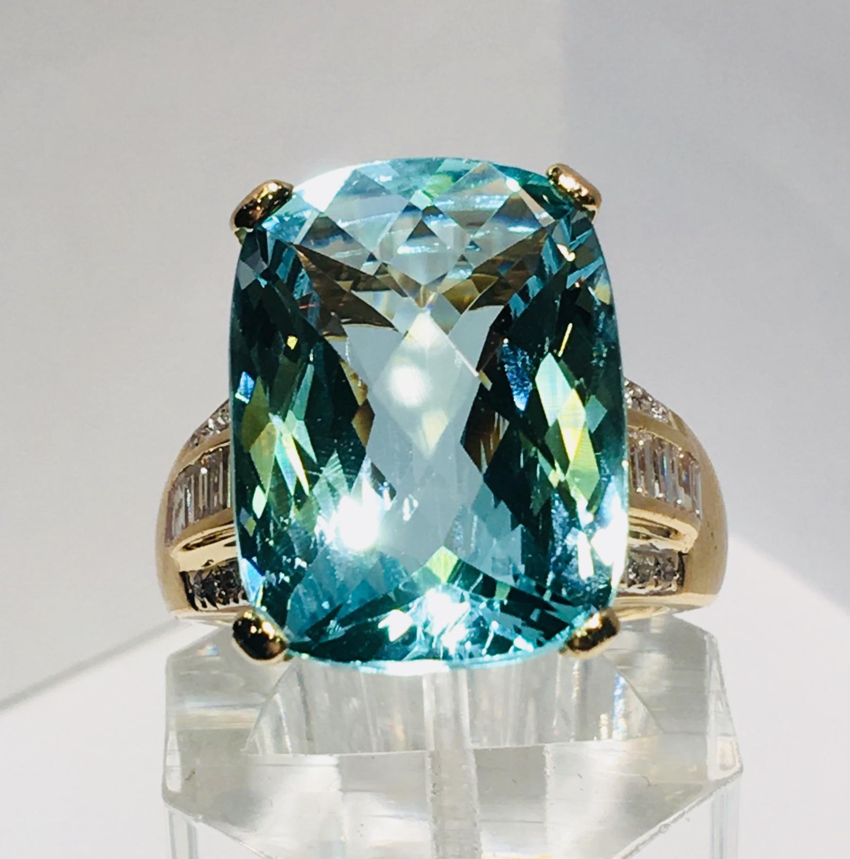 Magnificent 14 karat yellow gold estate ring features a prong-set, checkerboard cut, rectangular aquamarine, which is flanked by a row of channel-set baguette diamonds between two rows of round brilliant, pave set diamonds.

Aquamarine measures