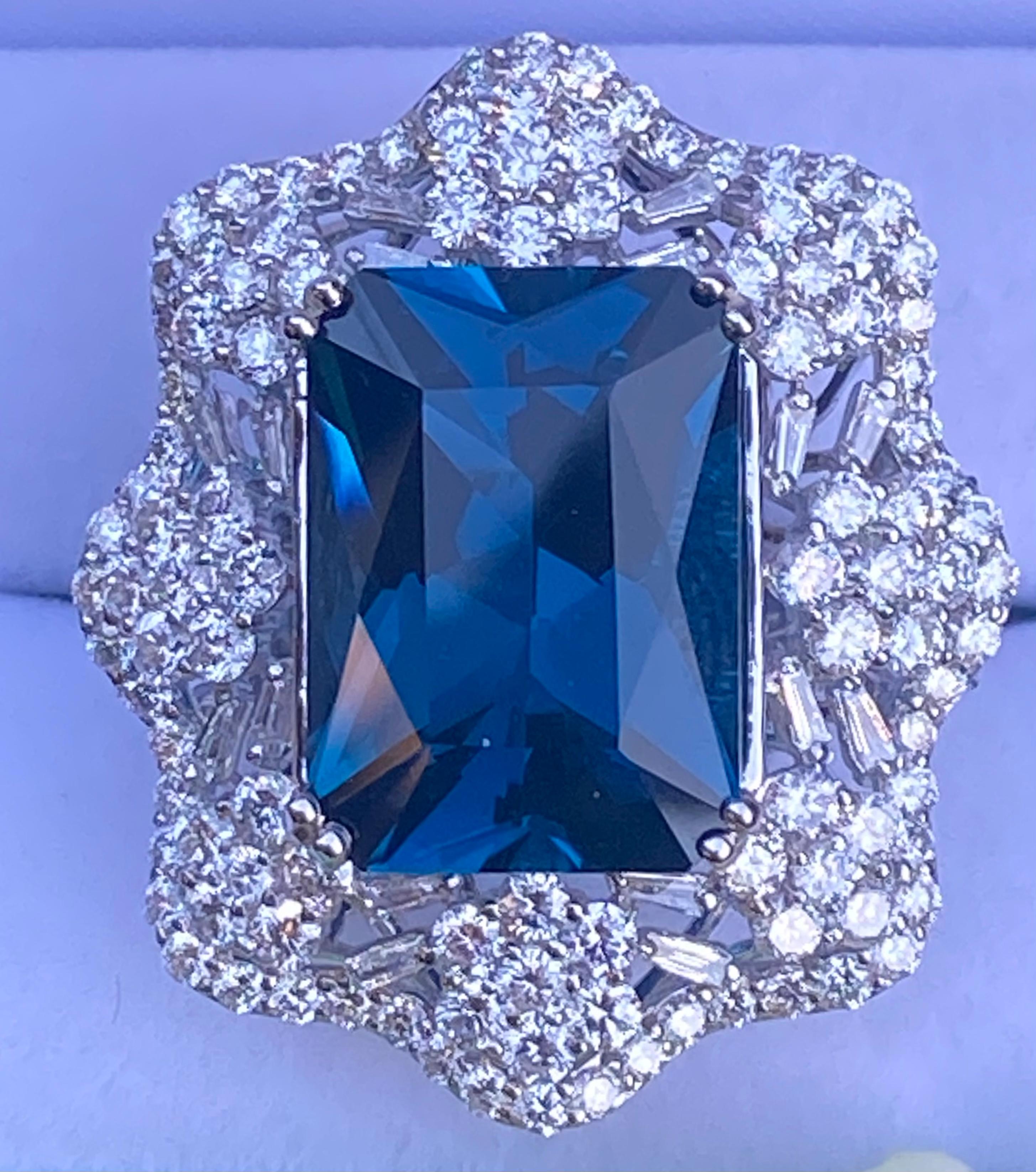 Stunning, very large, estate 18.17 carat deep London blue topaz is double talon prong set in 18 karat white gold and surrounded by approximately 162 round brilliant and baguette cut diamonds in a magnificent scalloping design mounting with a flower
