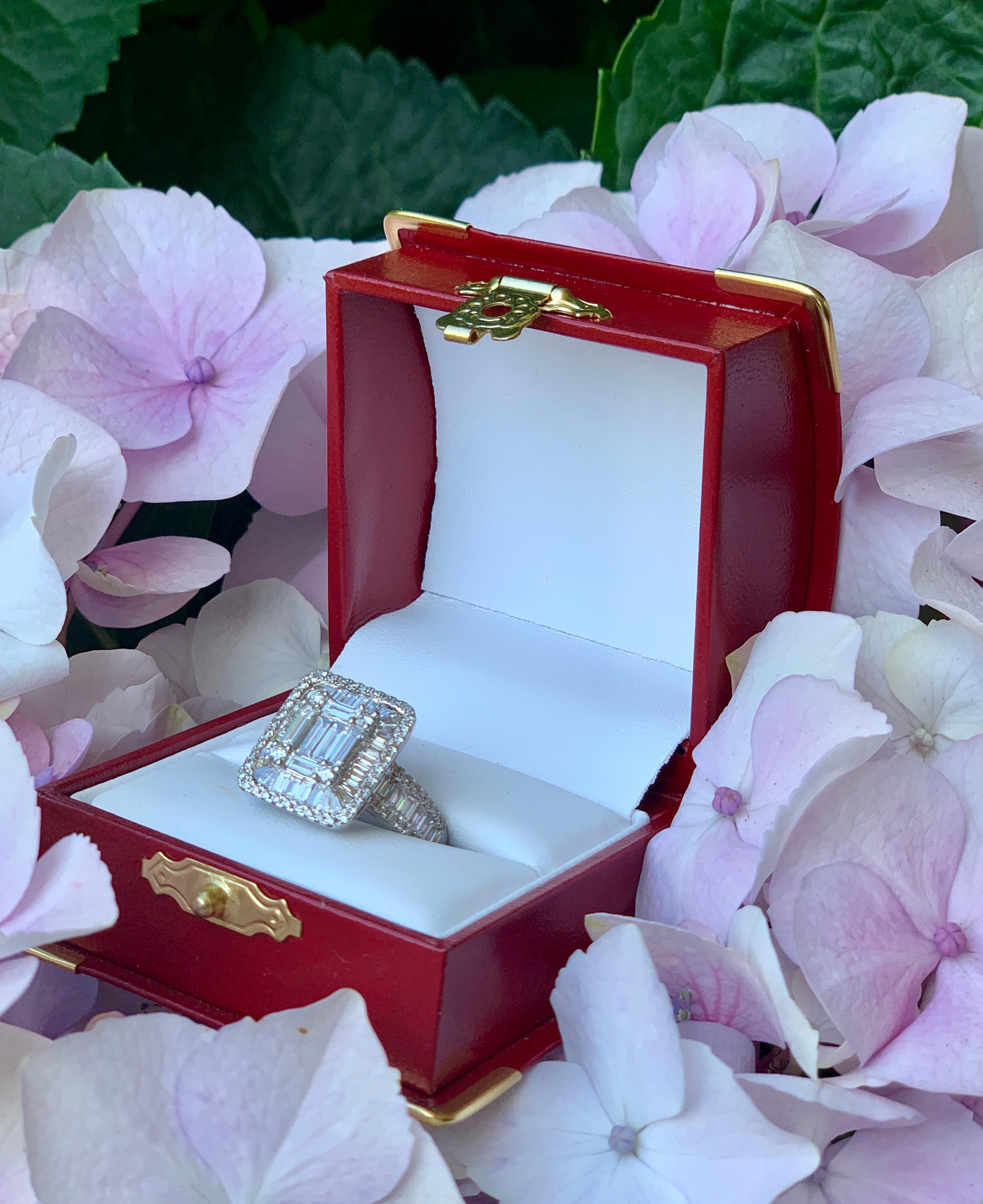 Invisibly set baguette diamonds are accented by prong set and u-set round diamonds in this fantastic 18 karat white gold estate ring, which gives the illusion of a very large, cut corner step cut rectangular diamond.

6 straight baguette and 4 round