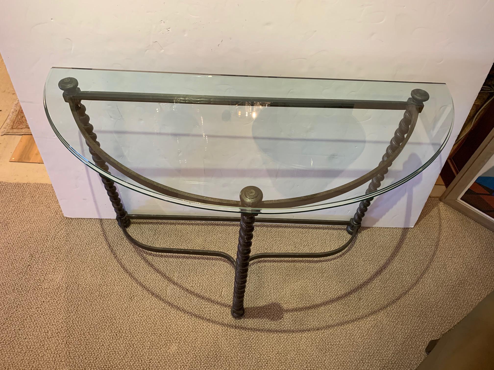A very versatile handsome crescent shaped console table having dark iron base with 3 barley twist legs, ball tops and feet, and substantial beveled glass top.