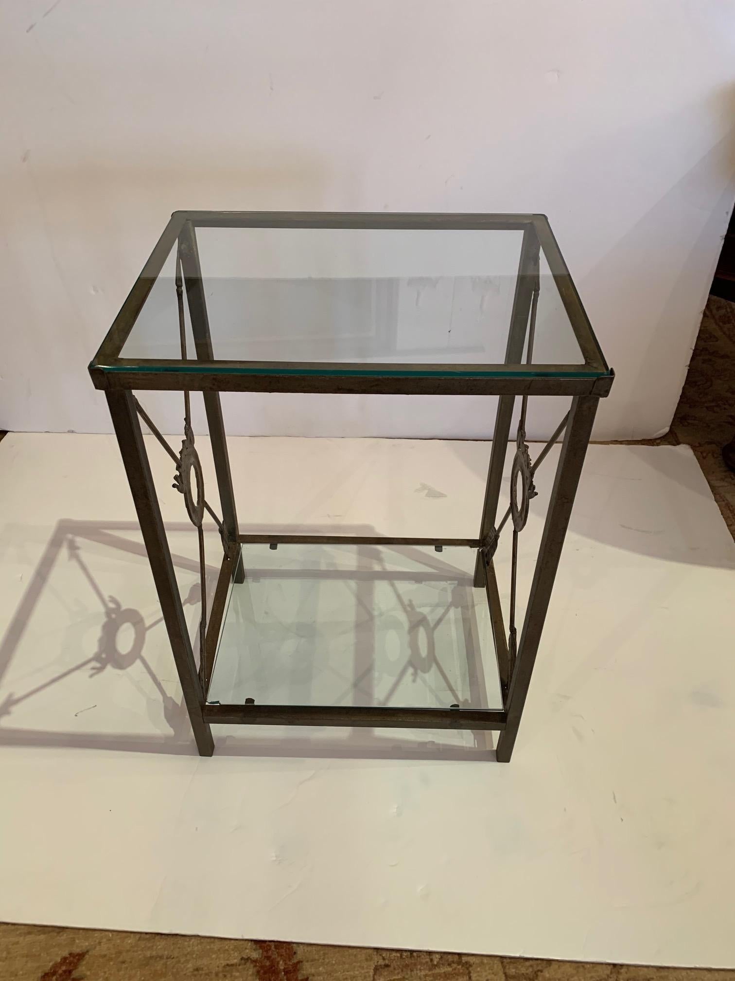 A versatile medium sized two-tier end table having aged metal frame with arrows in a neoclassical or Empire style. The two tiers are glass.