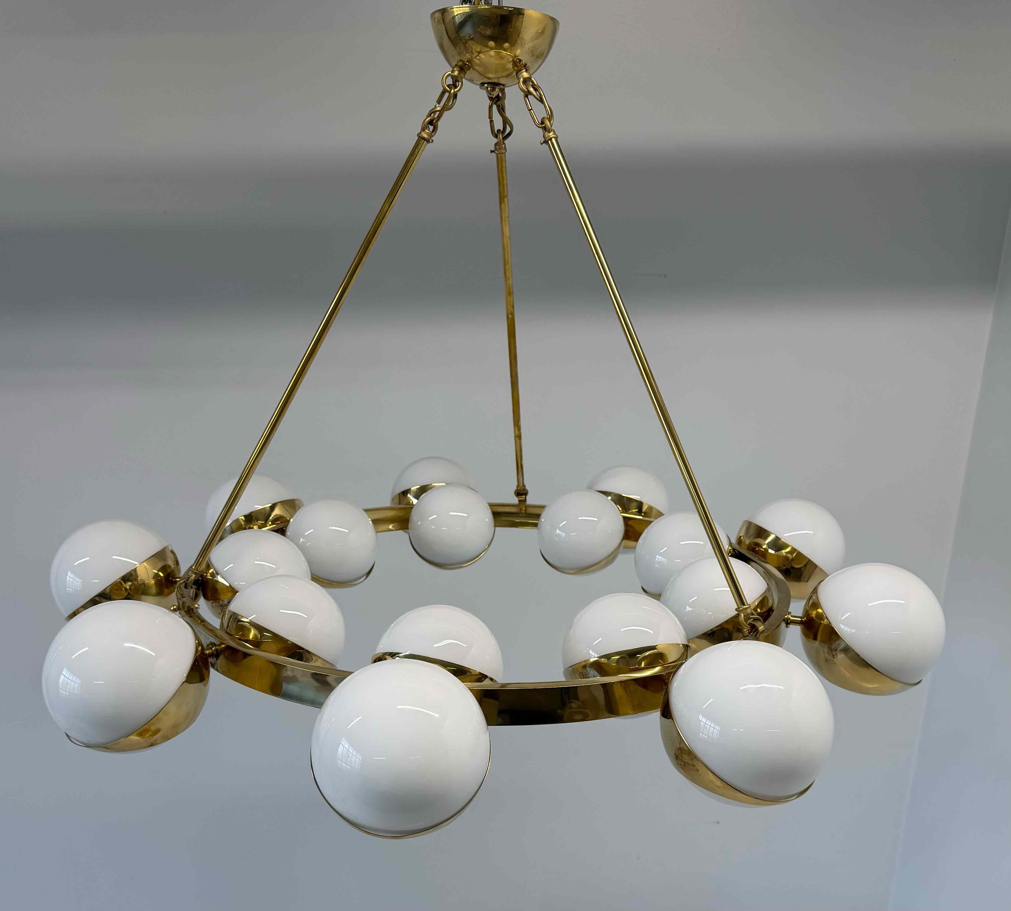 Stupendo lampadario italiano con struttura in ottone lucido e diciotto globi in vetro di Murano bianco latte.
Il design presenta una struttura circolare in ottone che sostiene le sfere di vetro soffiato, ciascuna parzialmente incastonata in coppe di