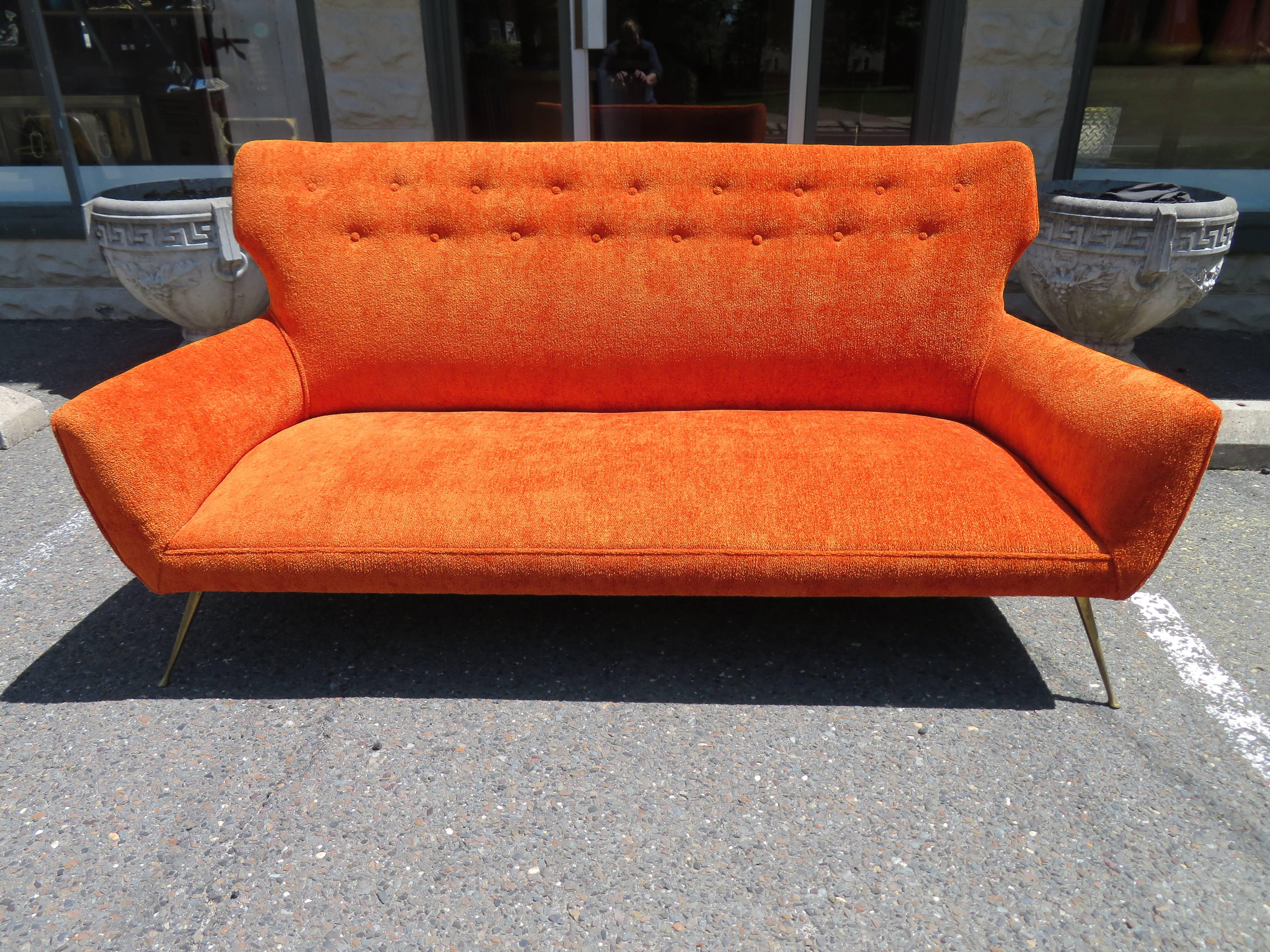 Stunning Italian modern Gio Ponti inspired sofa with splendid delicate brass splayed legs. The original vibrant orange chenille style fabric is still in wonderful condition and the foam and straps are very comfortable also. This is one of those