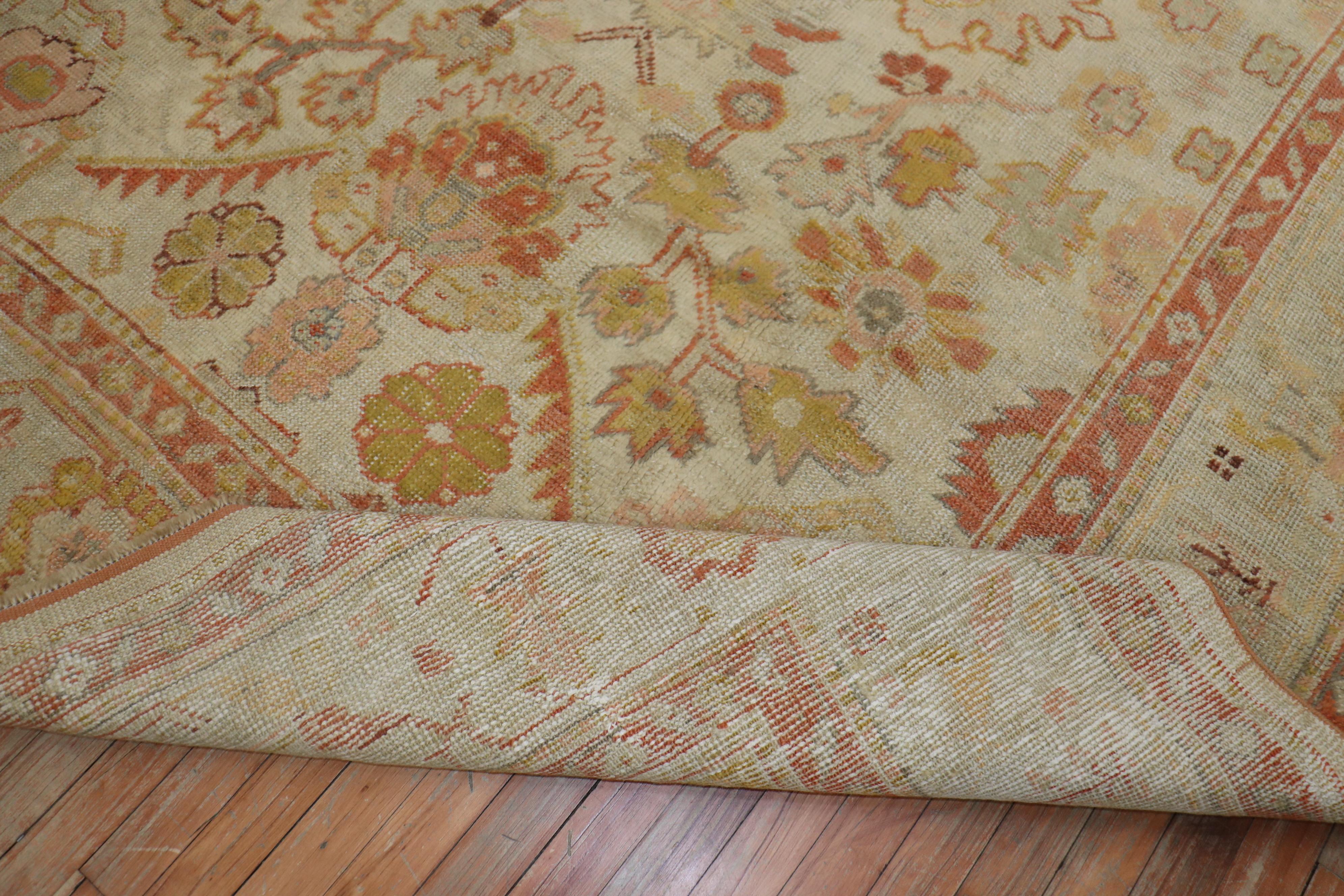 An early 20th century antique Turkish Oushak carpet with an all-over design on an. Ivory field, dominant accents in orange.

Measures: 7' x 9'6''.