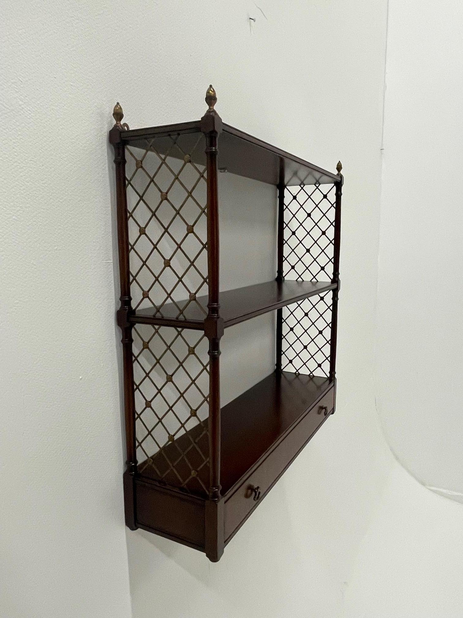 Beautiful two tier mahogany wall shelves having lovely brass lattice work on the sides and handsome brass finials. A great piece for displaying objects d'art.