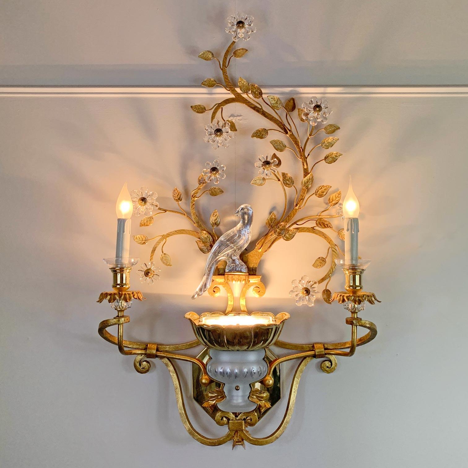 An absolutely incredible wall light by Banci Firenze, Italy, of huge proportions. The wrought, gilt iron frame, profuse in crystal flowers throughout, to the centre a large crystal parrot, the two arms of the lamp holders stretch out to either side,