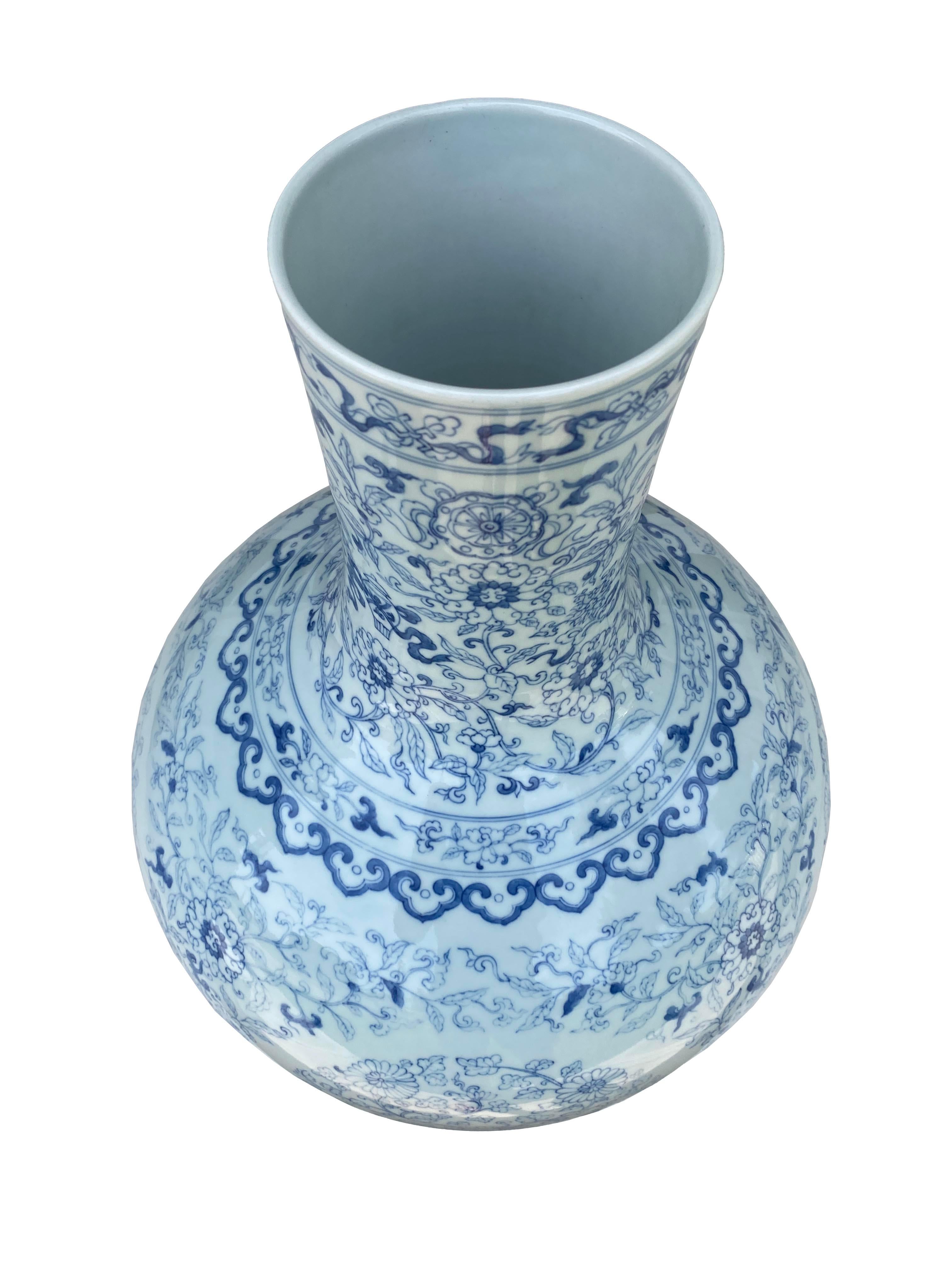 A stunning large Chinese porcelain vase. Crafted with meticulous attention to detail, it boasts a hand-painted pale blue and white finish, adorned with delicate floral motifs that exude a sense of serene beauty. The gourd-shaped silhouette adds a
