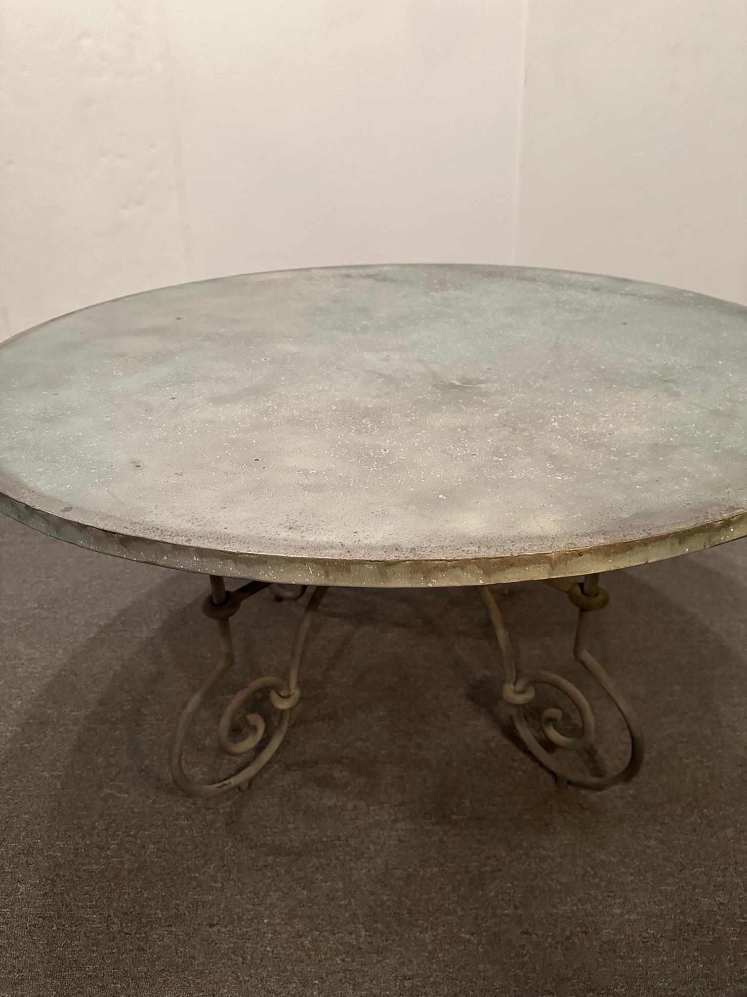 Handsome large round grey zinc topped dining table having curlicue French style iron base.  Top is 1” thick.
