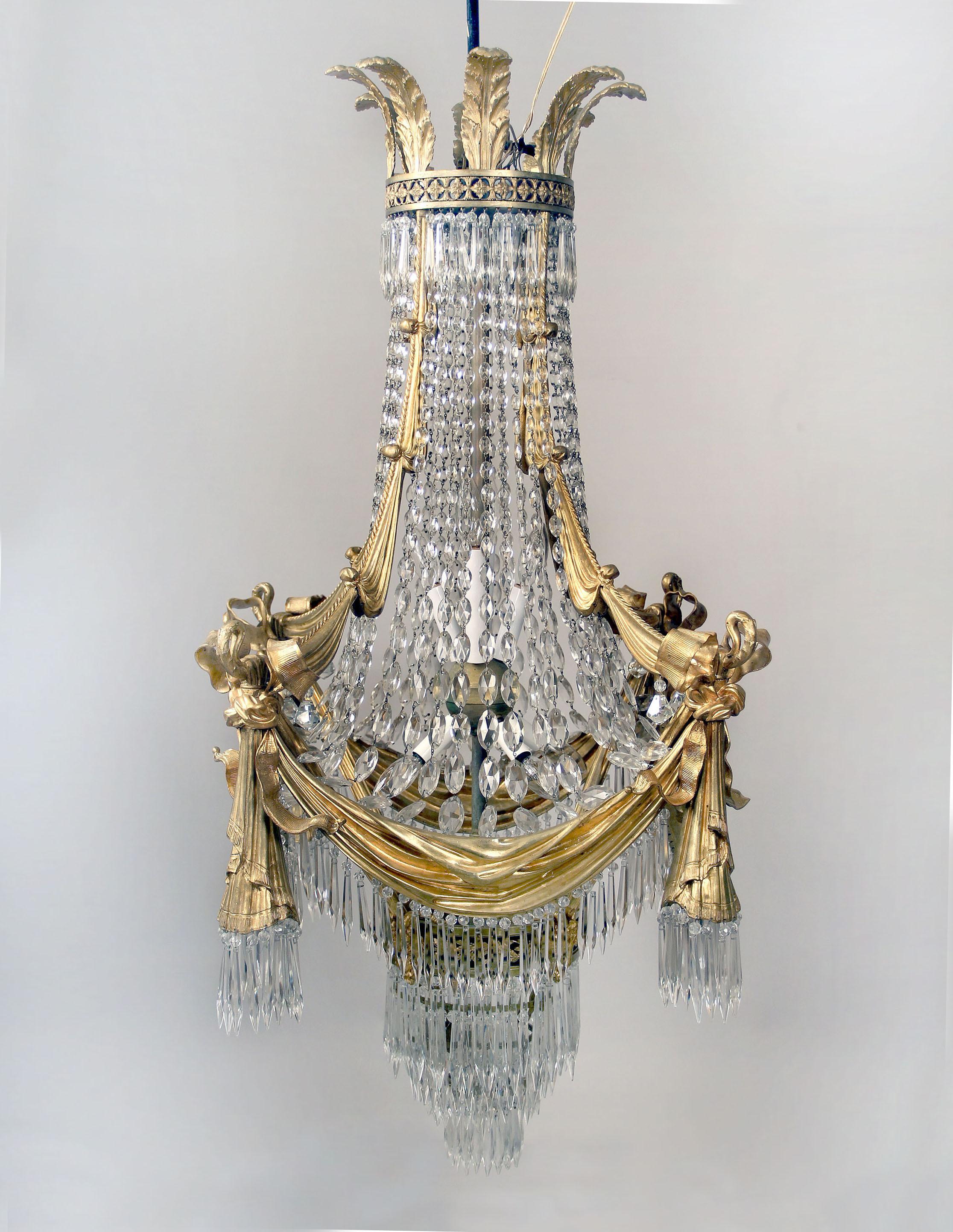 A stunning late 19th century gilt bronze and drop crystal fifteen-light chandelier

Great quality gilt bronze frame designed with curtains and bows, the crown with plumes and the base with four ram heads. Beaded crystal body with layers of drop