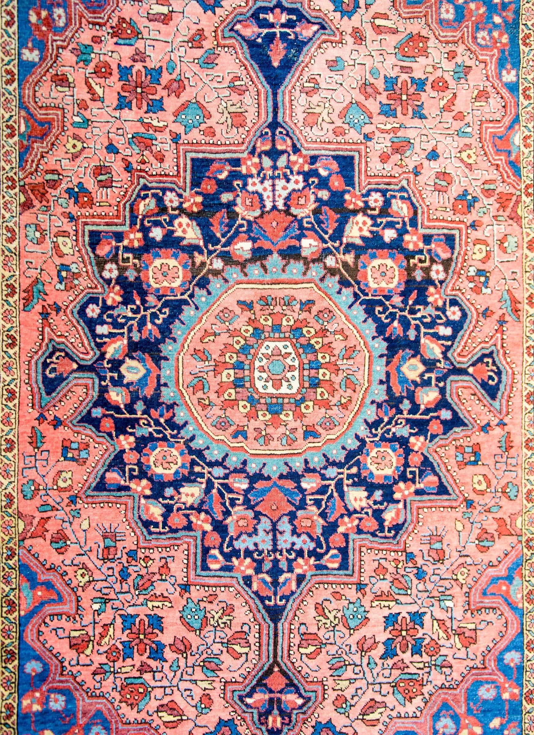 A wonderful early 20th century Persian Sarouk Farahan rug with an expertly rendered and densely woven central medallion containing a pattern of intertwining vines, leaves, and flowers woven in beautiful indigo, salmon, crimson, and gold yellow