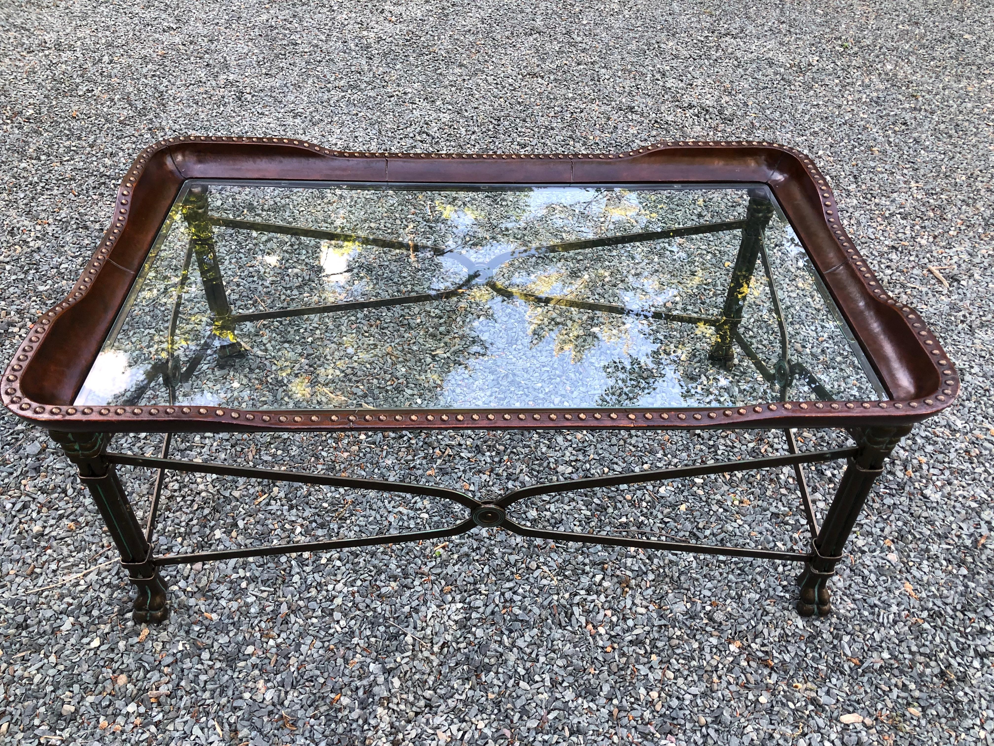 Very handsome Regency style iron and leather rectangular coffee table with lion paw feet. The table has metal stretchers, a deep brown leather surround with brass nailheads, and glass top. 

 