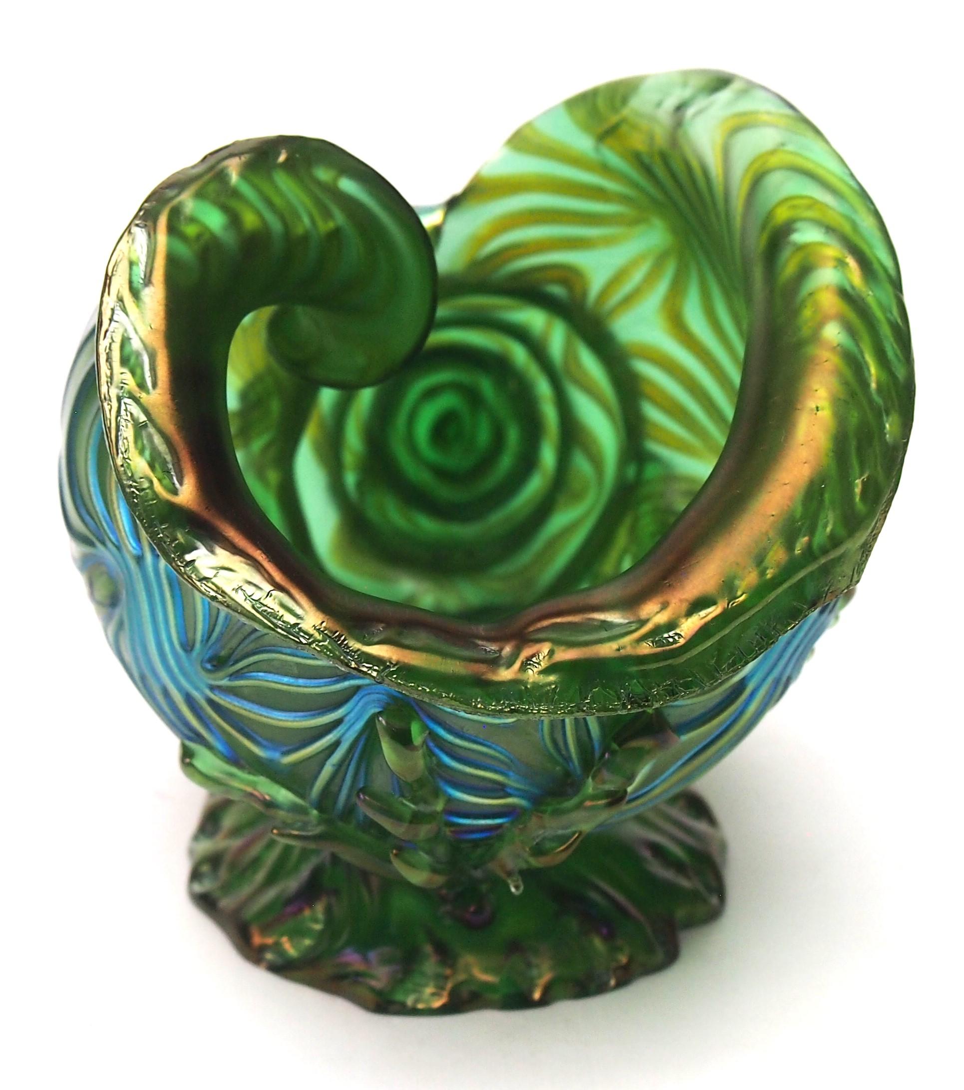 A Loetz Crete Formose seashell vase in green with blue highlights; an effect designed to look like waves - hence the name. The spiral Seashell appears to reside on a rocky outcrop 'at the bottom of the sea' and is surrounded by fine seaweed trails.