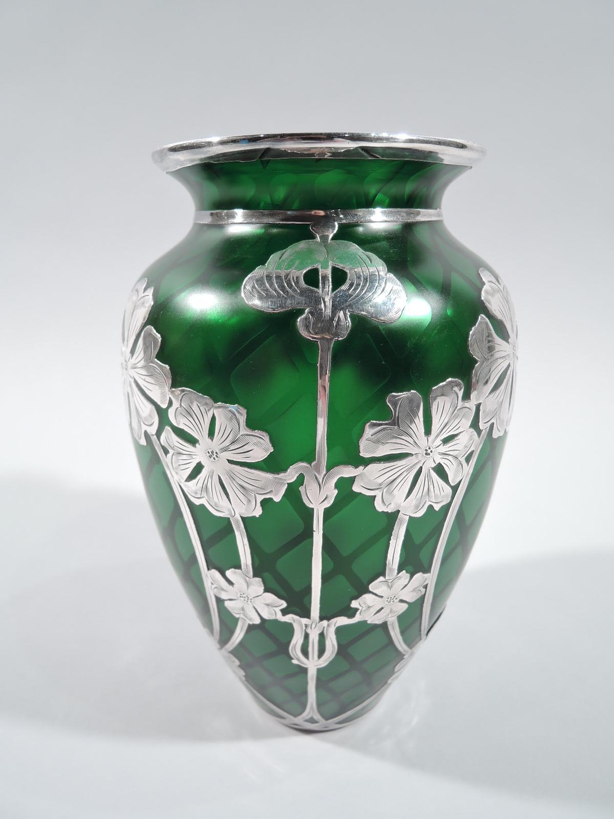 Stunning turn-of-the-century quilted glass vase by historic Loetz with engraved silver overlay. Ovoid with short neck and flared rim. Glass green with light diaper pattern on dark ground. Silver overlay in vertical floral pattern with straight and