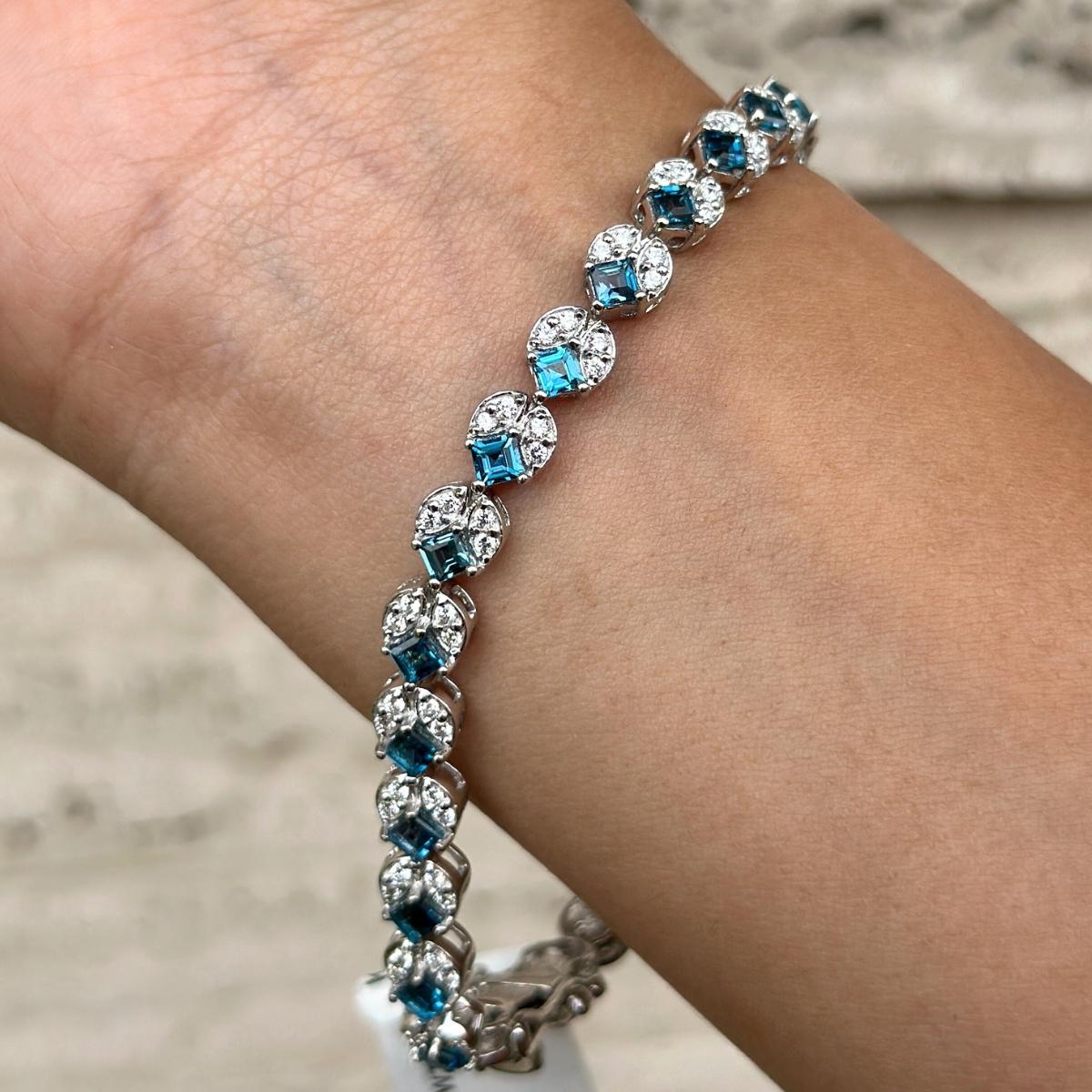 Le superbe bracelet de tennis en argent sterling orné de topazes bleues de Londres et de diamants met en valeur des topazes bleues de Londres naturelles d'un poids de 7,88 carats, étincelantes à l'infini. Il mesure 7.5 pouces de long. 
La topaze