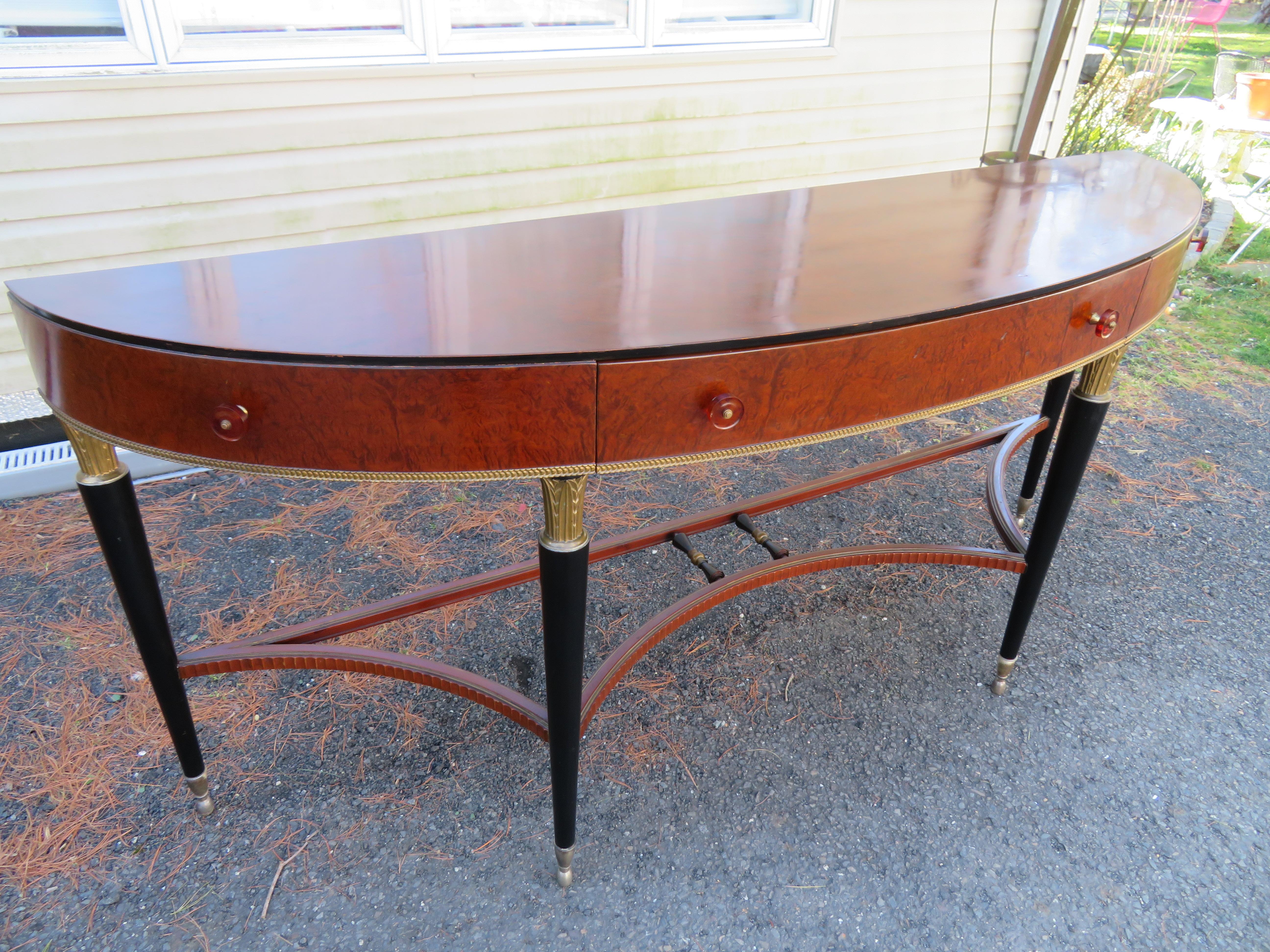 Exquisite French Louis XVI-style flamed mahogany demi-lune console table. One dovetailed drawer with lovely bakelite and brass pulls. The elegant tapered ebonized legs have lovely hand-carved gilded acanthus capitals and terminate with interesting