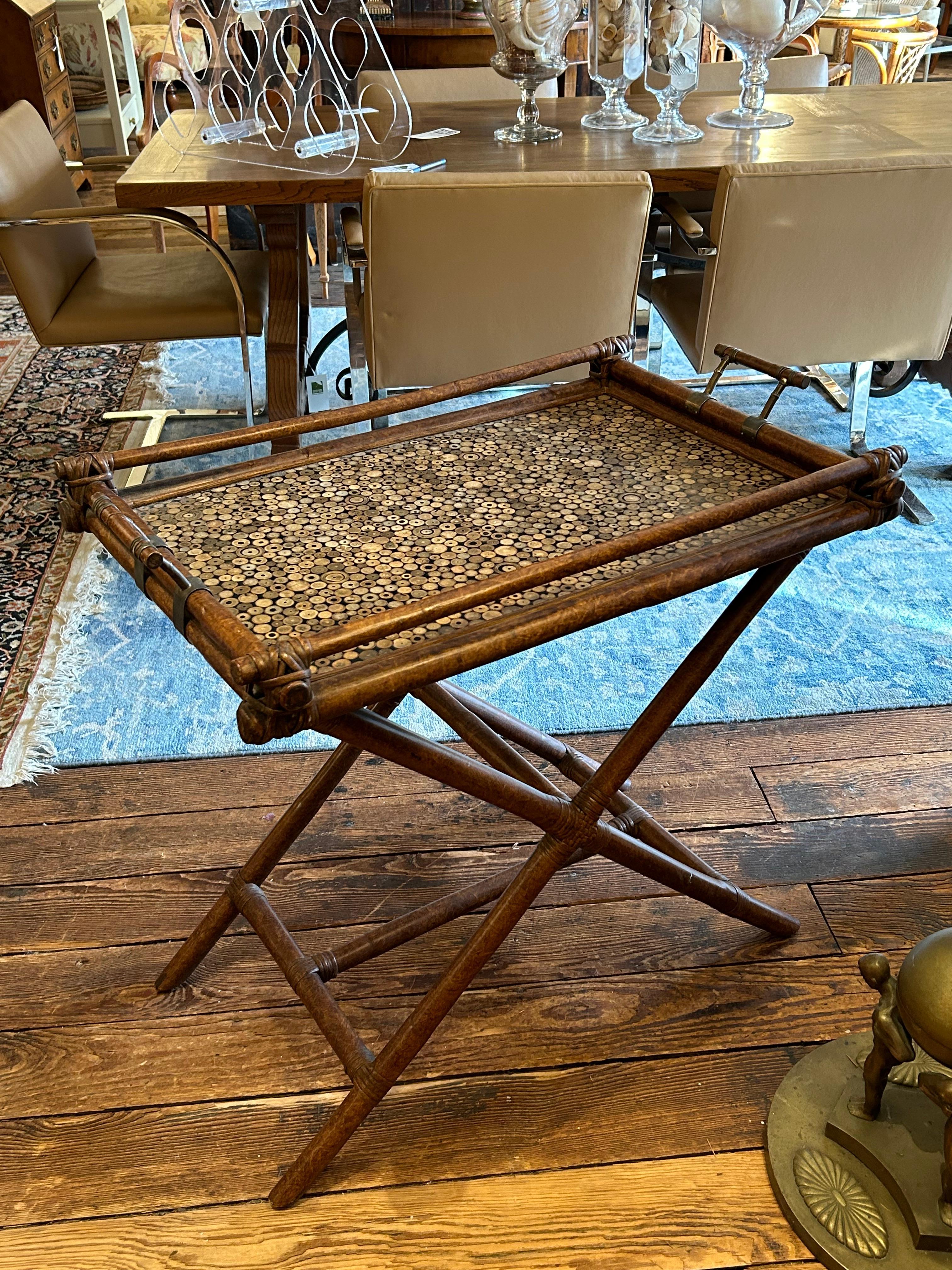 Table de bar à plateau élégante avec plateau amovible ;  Style Campaigner avec une belle finition marron chaud et des articulations enveloppées de cuir.  Le plateau présente une surface fascinante avec des incrustations en forme de Cheerio qui ont