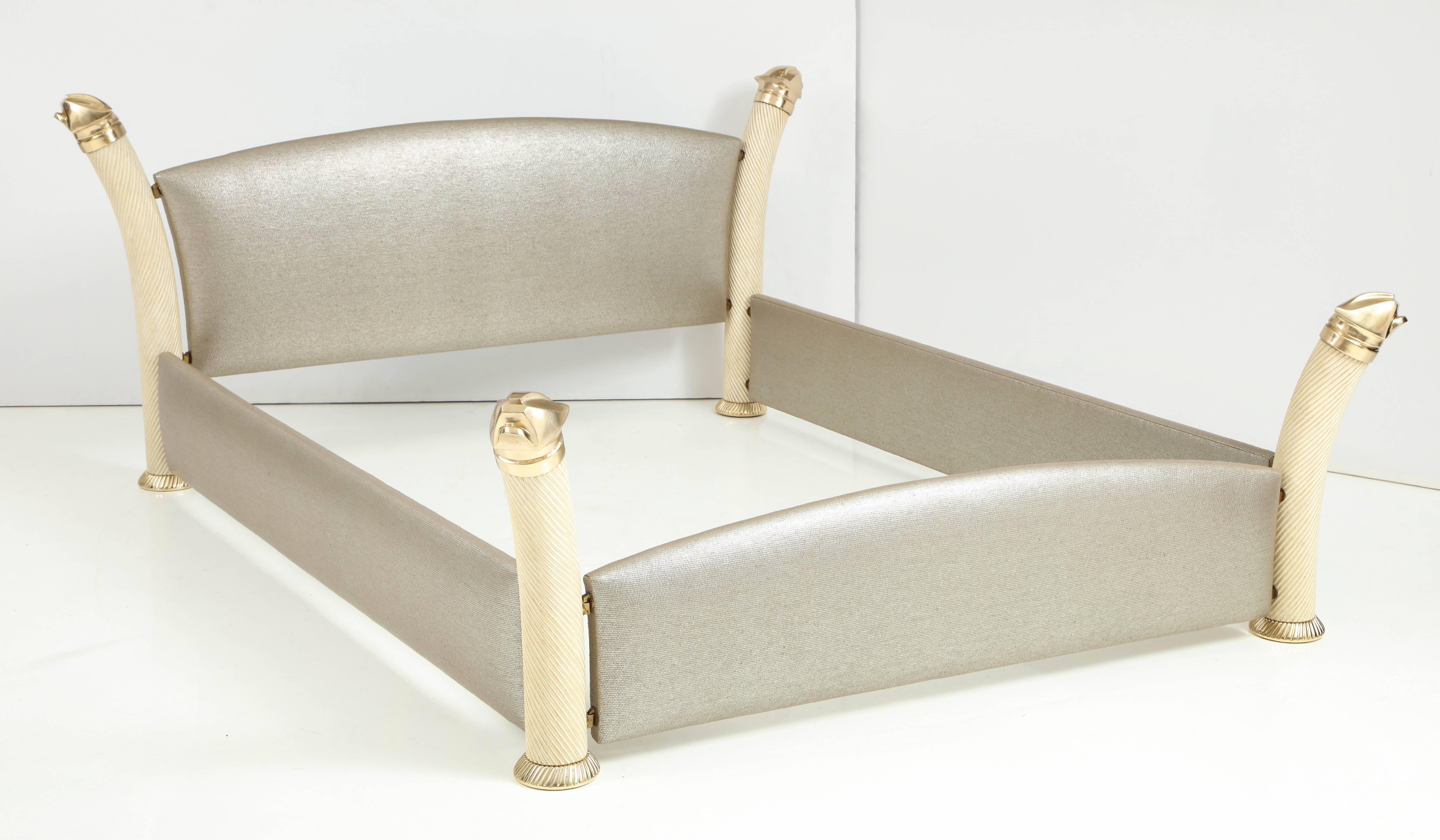 Glamorous 1980s Queen size bed by Italian furniture designer Marcello Mioni.
The bed frame is made of four carved wood spiral posts with a faux Ivory finish that are capped with polish brass stylized Jaguar heads. The headboard and side rails have