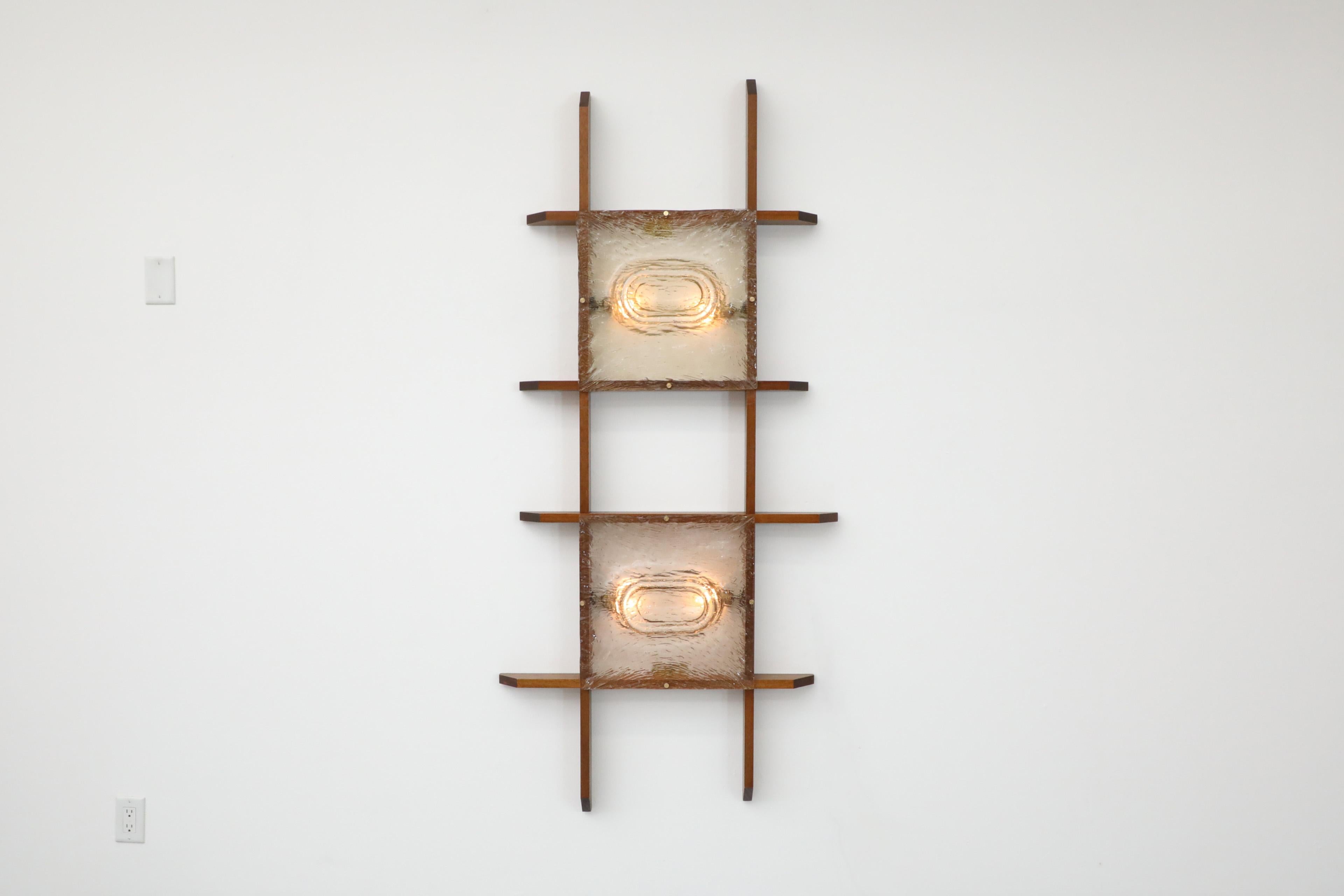 Mid-Century Mazzega attributed teak grid framed wall lights with two organic slump molded glass plate shades. Unique design that is a truly illuminating conversation starter. Can be hung vertical or horizontal. Three available in all with slightly