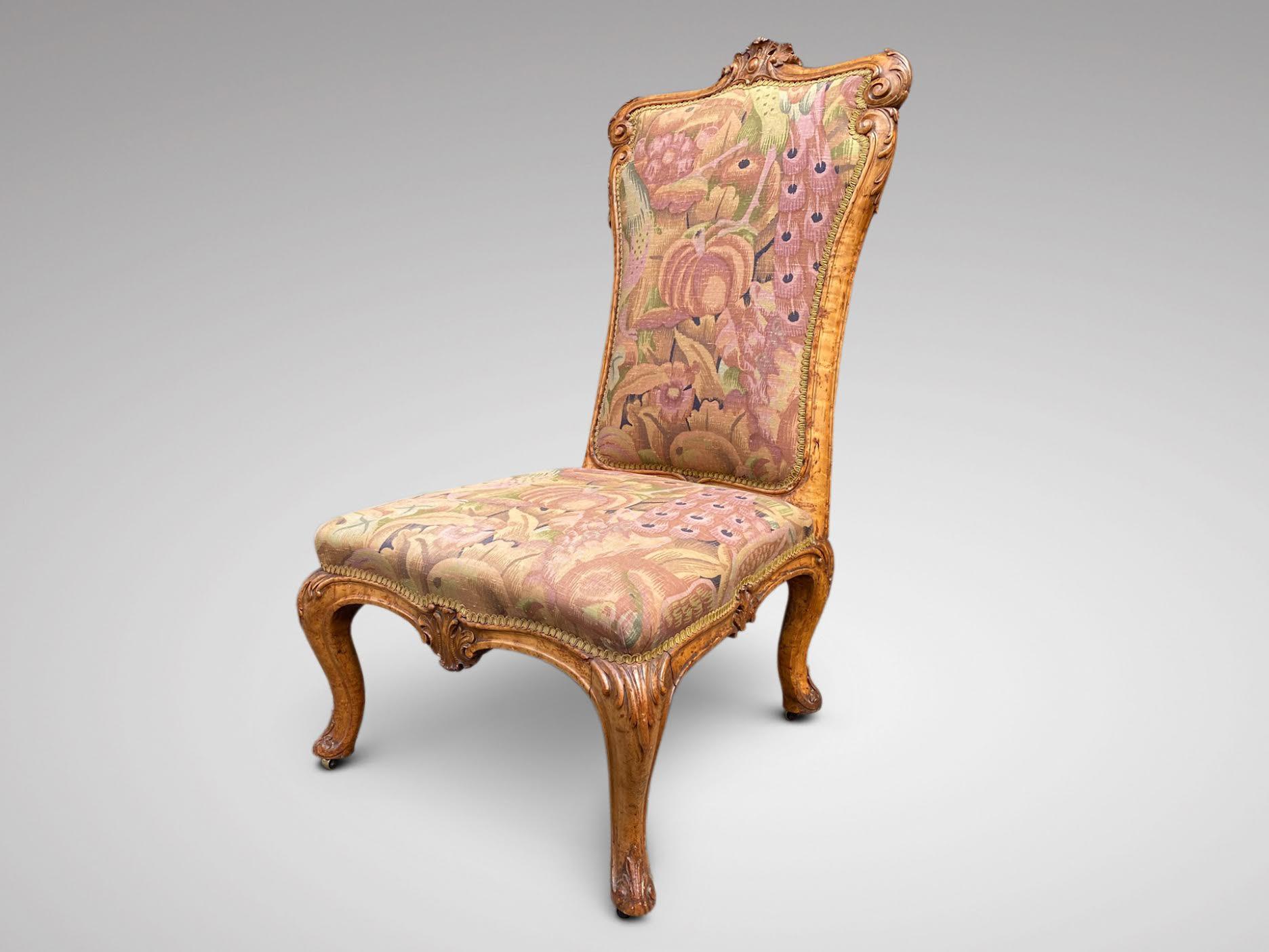 A mid 19th century, early Victorian period burr maple nursing chair. The burr maple foliate carved frame, with leaves head carved cresting rail, with upholstered back and set in a quality material. All standing up on beautifully foliate carved