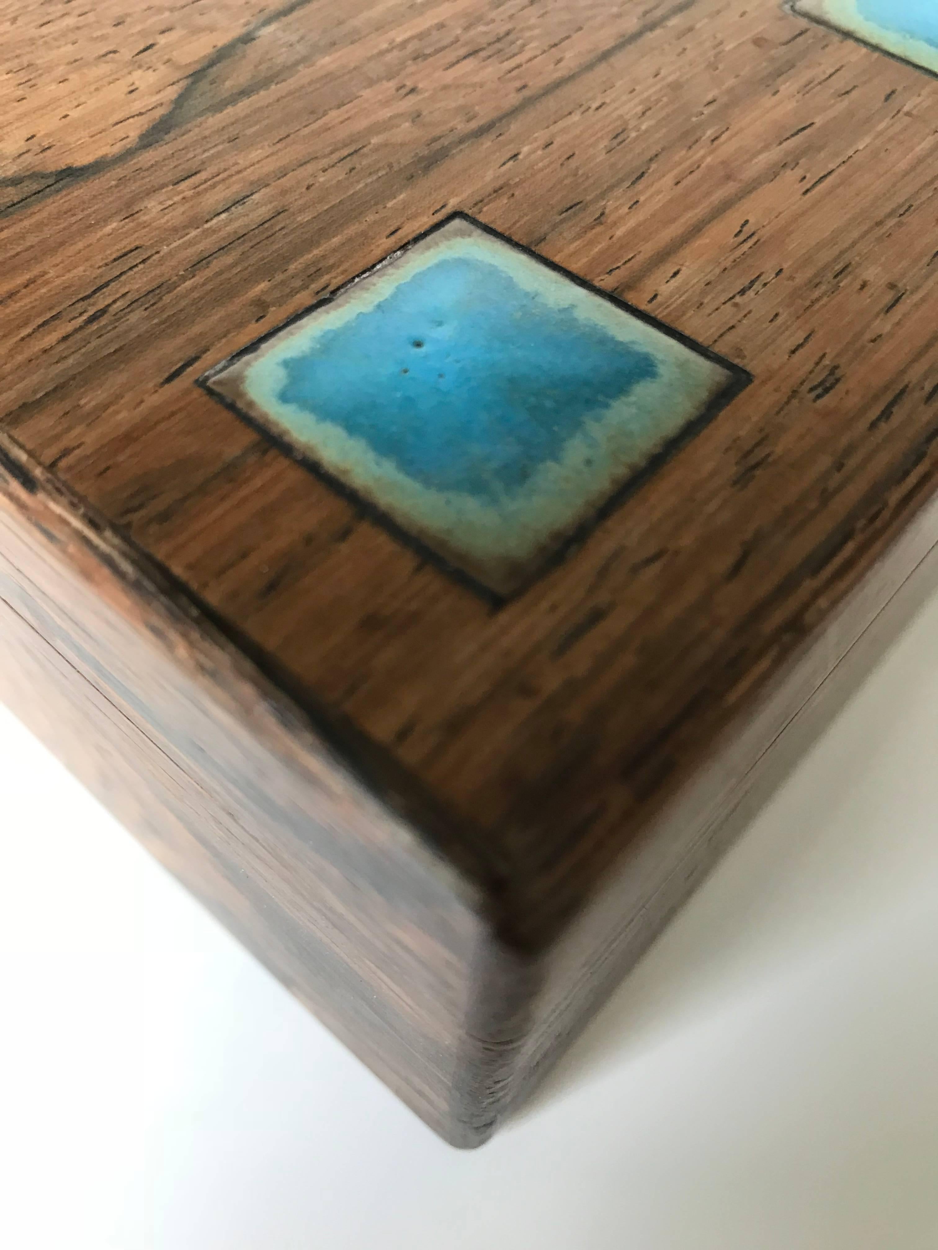 Beautiful midcentury craftsmanship box by Alfred Klitgaard.

This artistic design and all handcrafted square box of tropical hardwood is in excellent condition. We know that this one of a kind box is of a completely different era, but the colorful