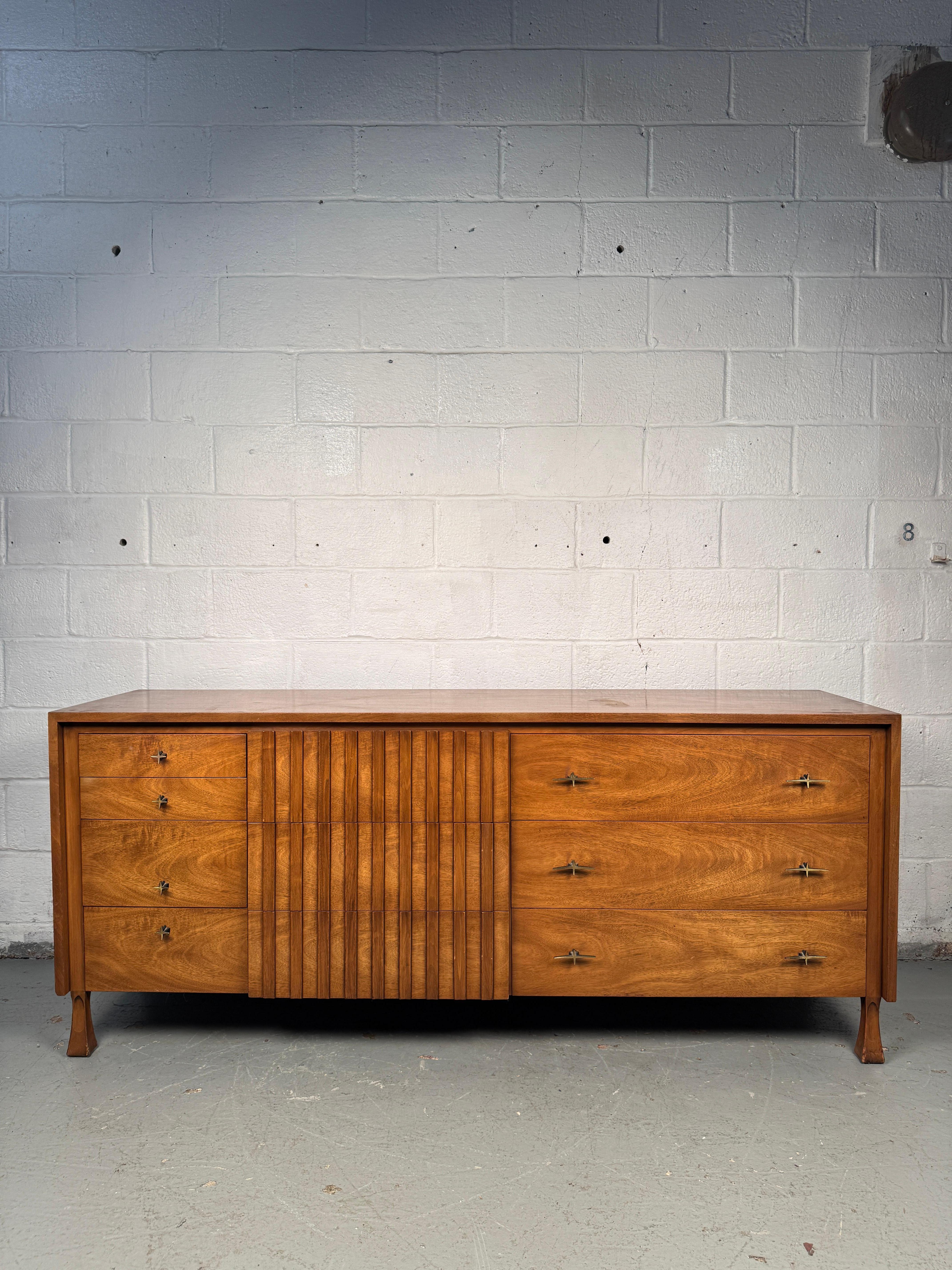 Exceptional mid-century dresser manufactured by John Widdicomb, crafted in richly figured wood The clean modernist form is elevated by the striking natural grain and warm tone of the wood. Modern, unique spacing of the drawers gives the piece a
