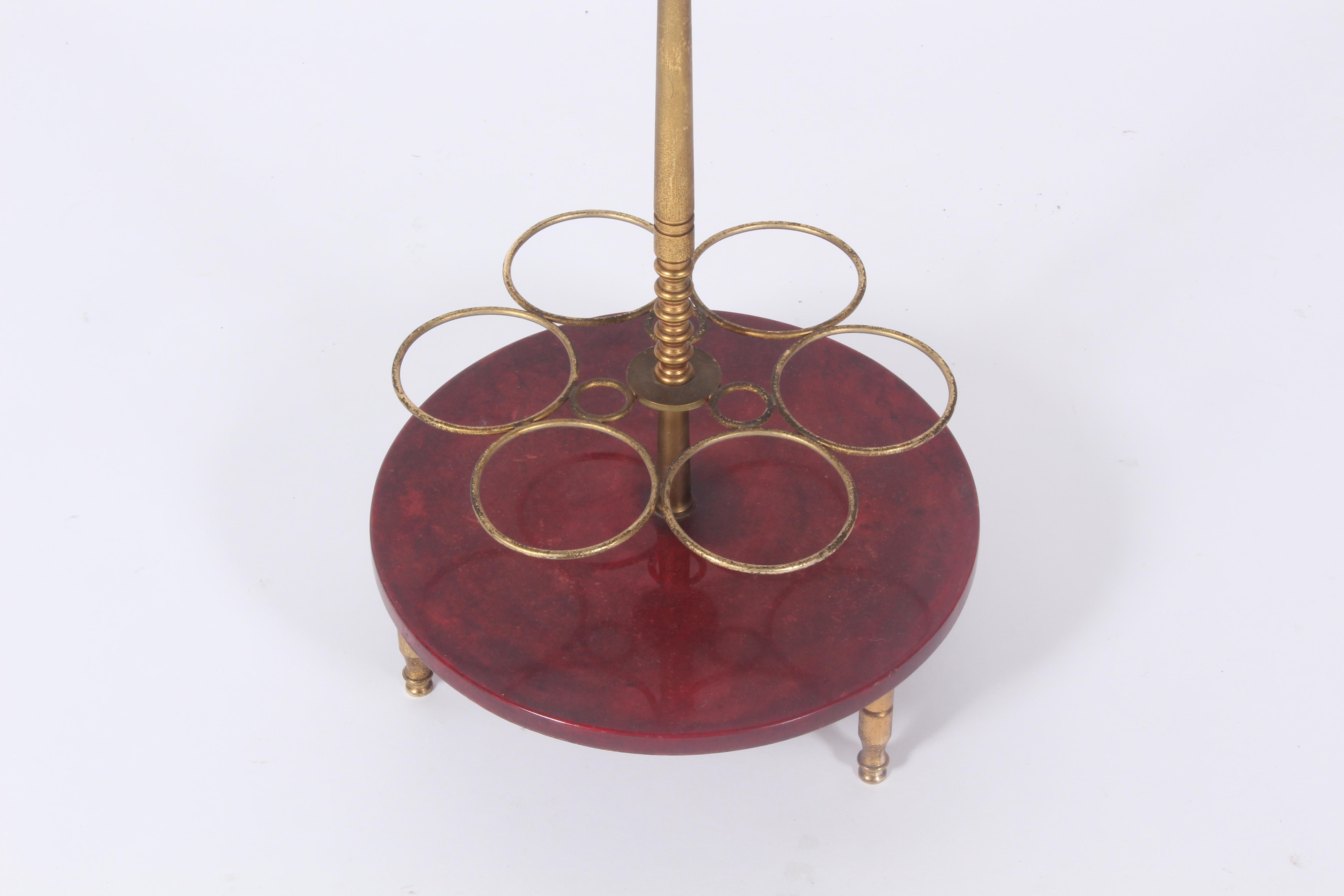 A fabulous bottle stand / centerpiece by the renowned Italian designer in brass wood and red parchment. In very good condition with some wonderful patina gained on the brass surfaces over the years. Bearing the original makers label to the