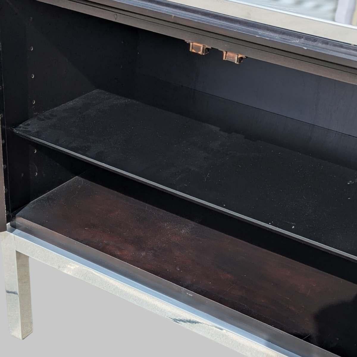 Presenting an exquisite Mid-Century Modern sideboard in the style of designs by Tommi Parzinger. Crafted in the late 1950s to 1960s, this stunning piece showcases a sleek, black stained wood body, accentuated by six ornate silver door pulls in